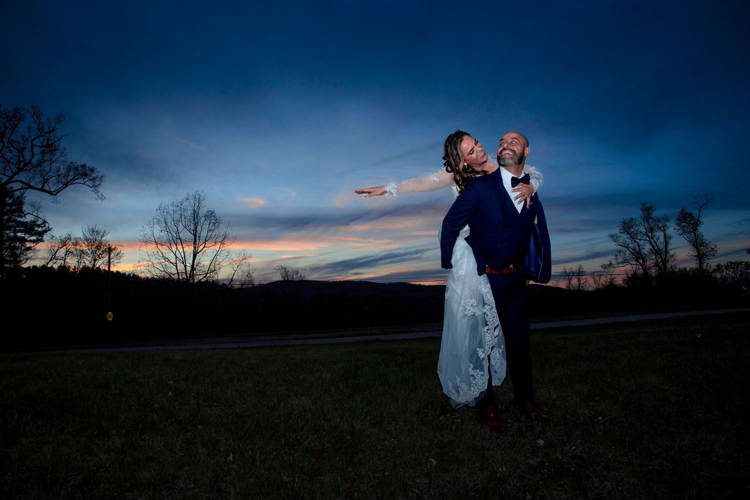 Dramatic sunset wedding photo with silhouetted couple against mountain backdrop.