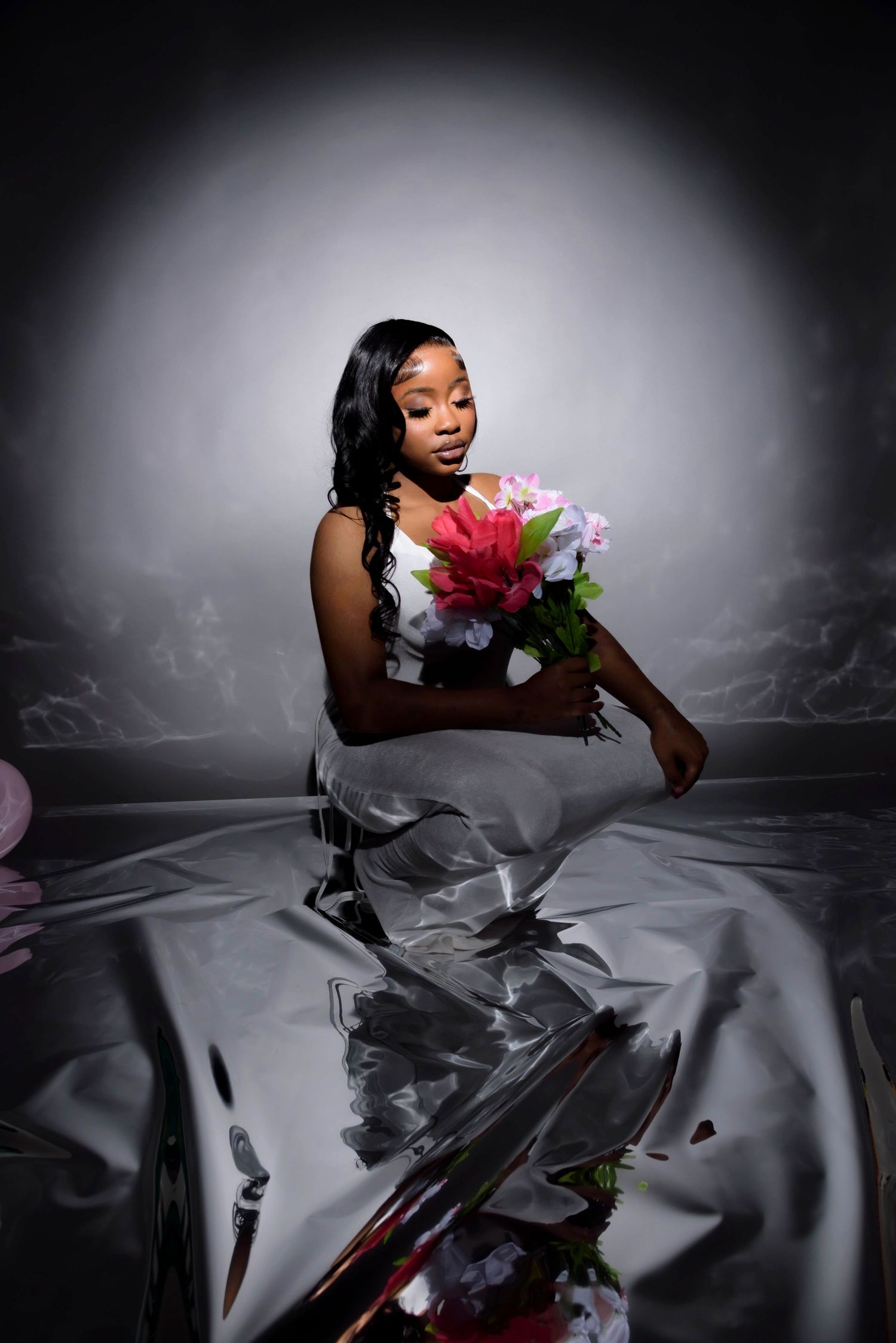 Elegant photo series with model in dark setting holding colorful flowers against reflective surface.