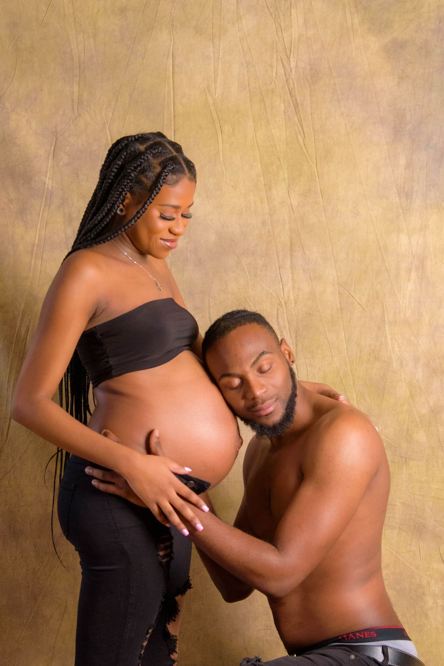 An intimate maternity photo featuring an expectant couple against a golden backdrop.