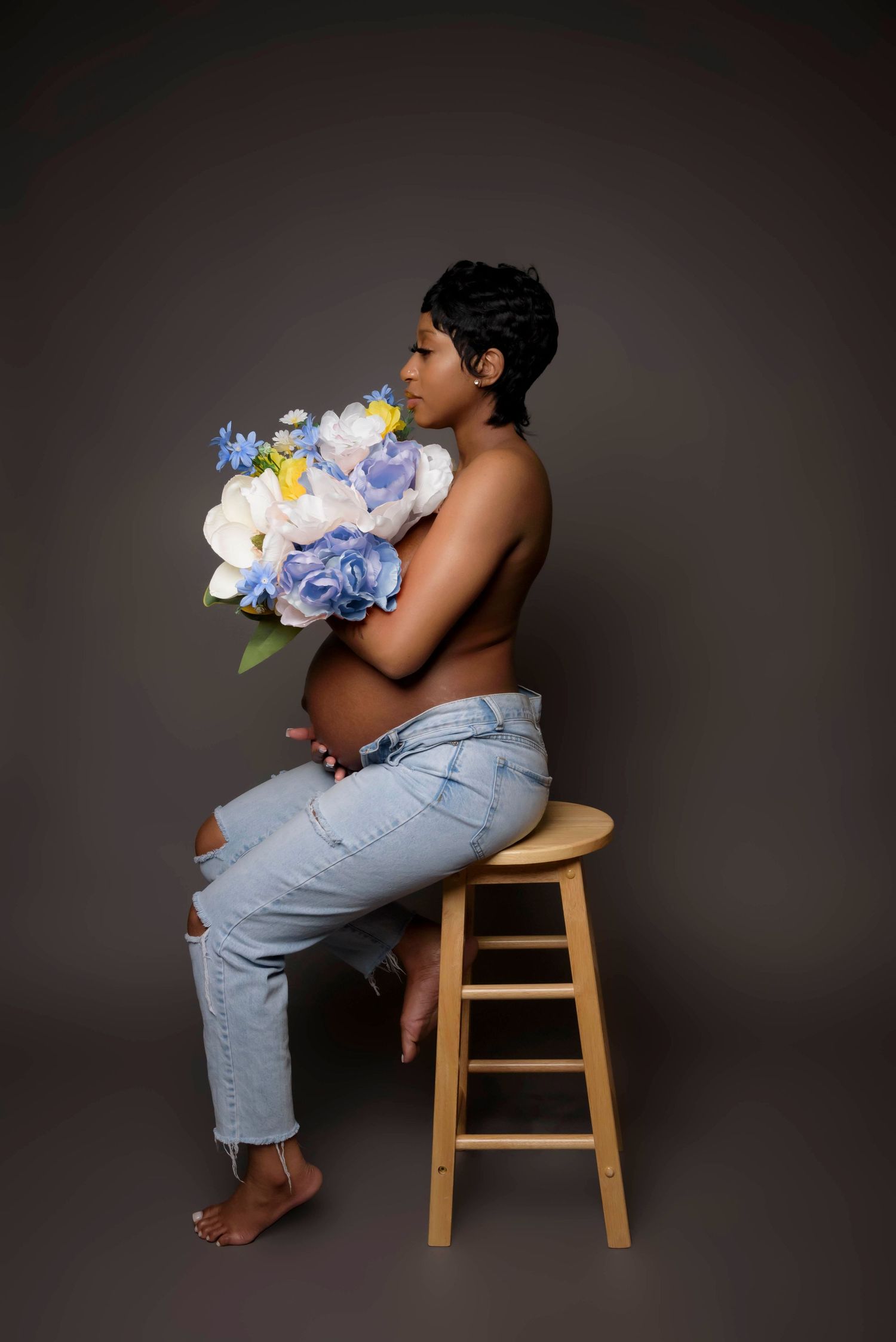 A maternity portrait featuring blue and white flowers against a dark background.
