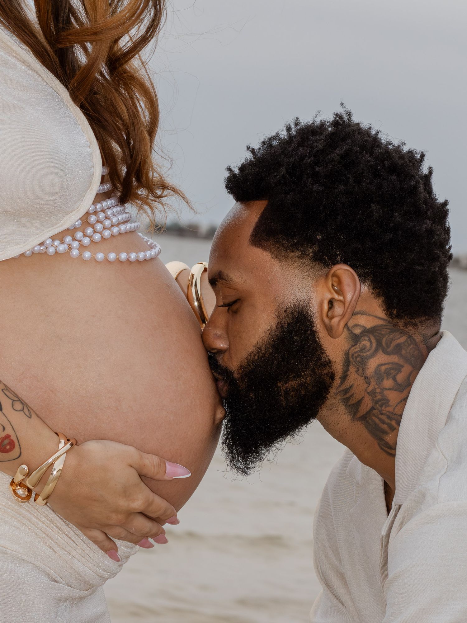 Couple embracing on Pensacola Beach during a sunset maternity photography session