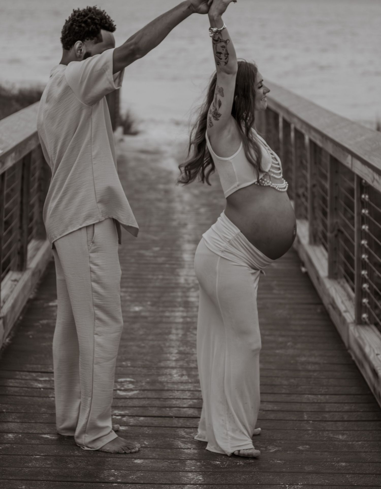 Couple embracing on Pensacola Beach during a sunset maternity photography session