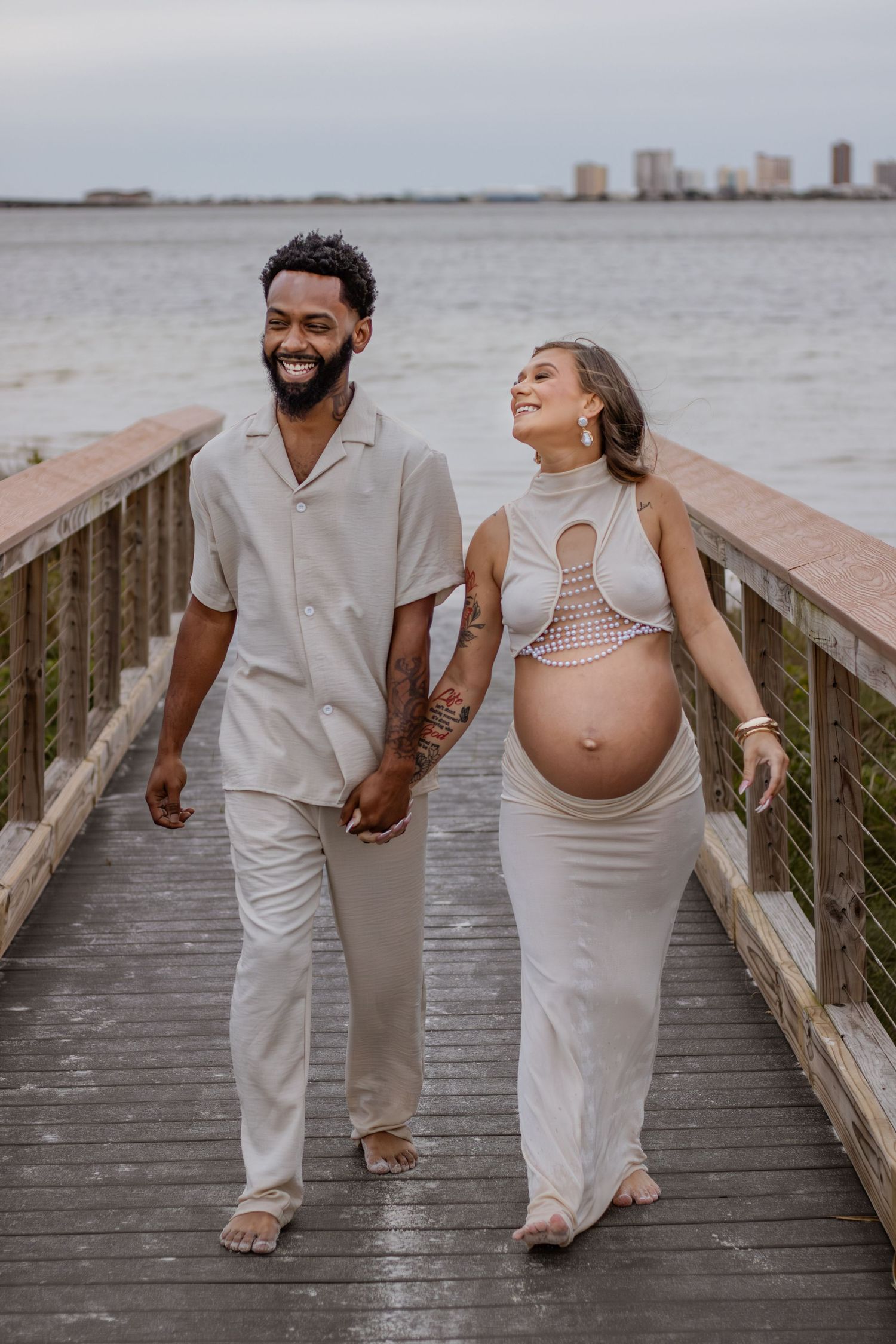 Couple embracing on Pensacola Beach during a sunset maternity photography session