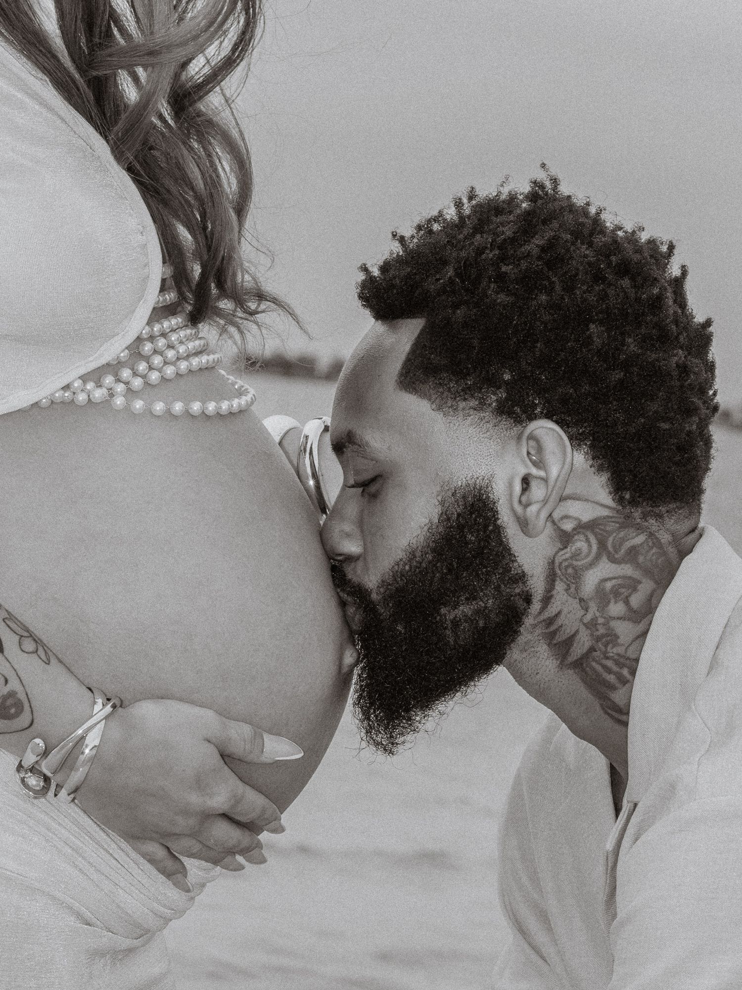 Couple embracing on Pensacola Beach during a sunset maternity photography session