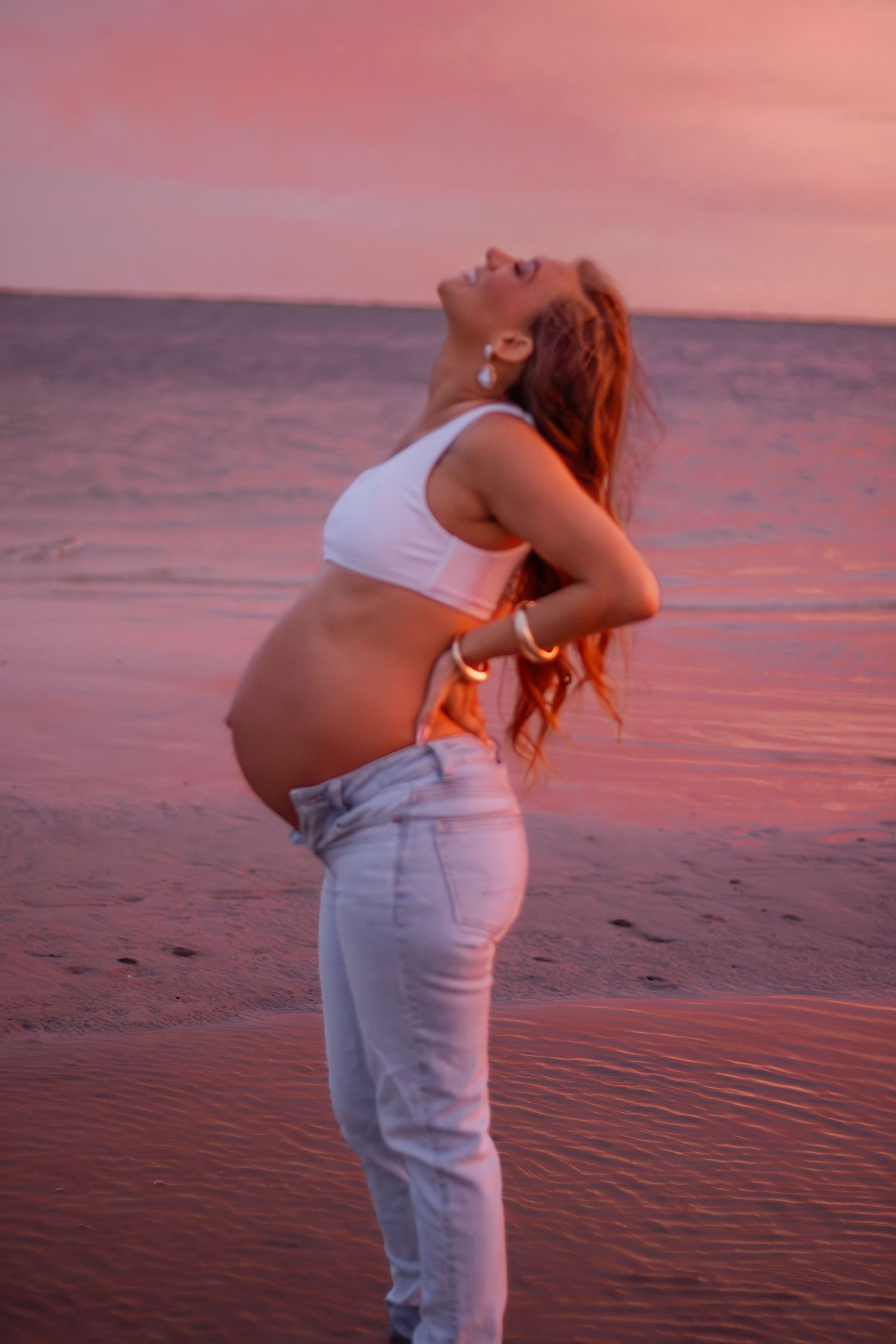 Couple embracing on Pensacola Beach during a sunset maternity photography session