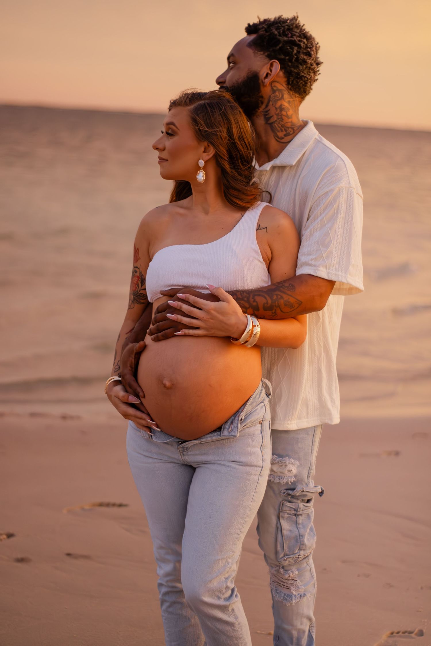 Couple embracing on Pensacola Beach during a sunset maternity photography session