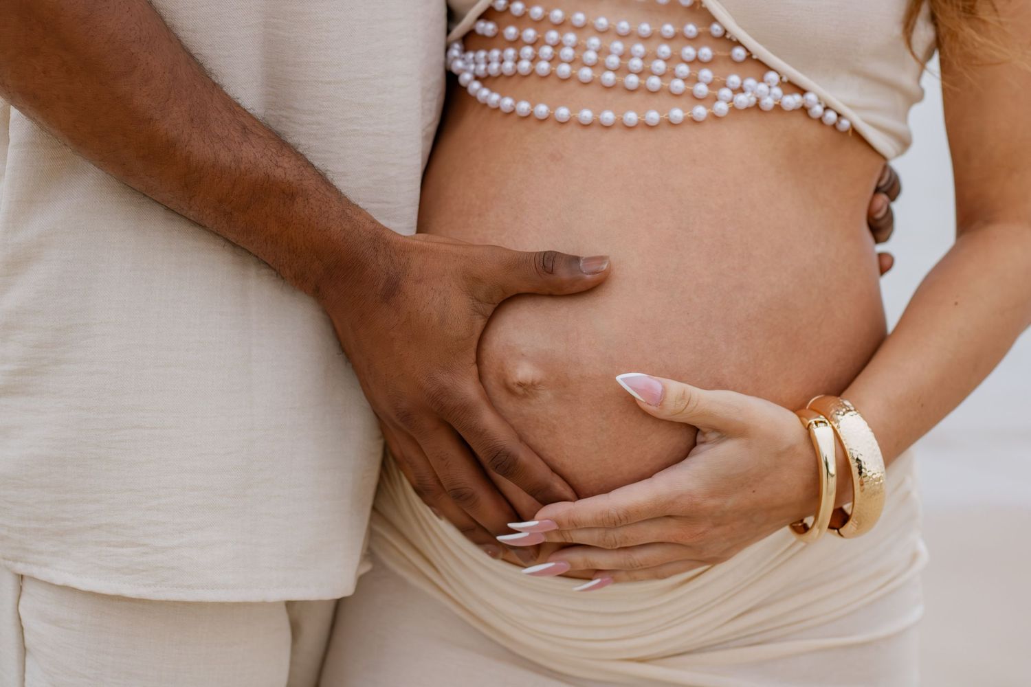 Couple embracing on Pensacola Beach during a sunset maternity photography session