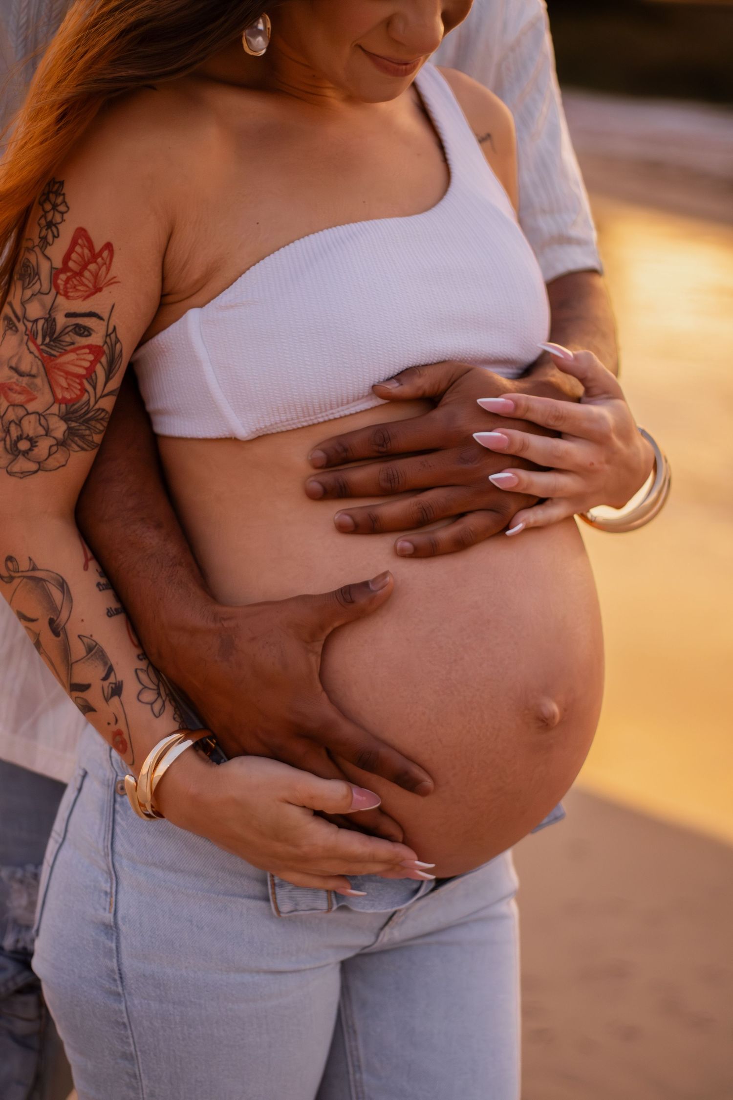 Couple embracing on Pensacola Beach during a sunset maternity photography session