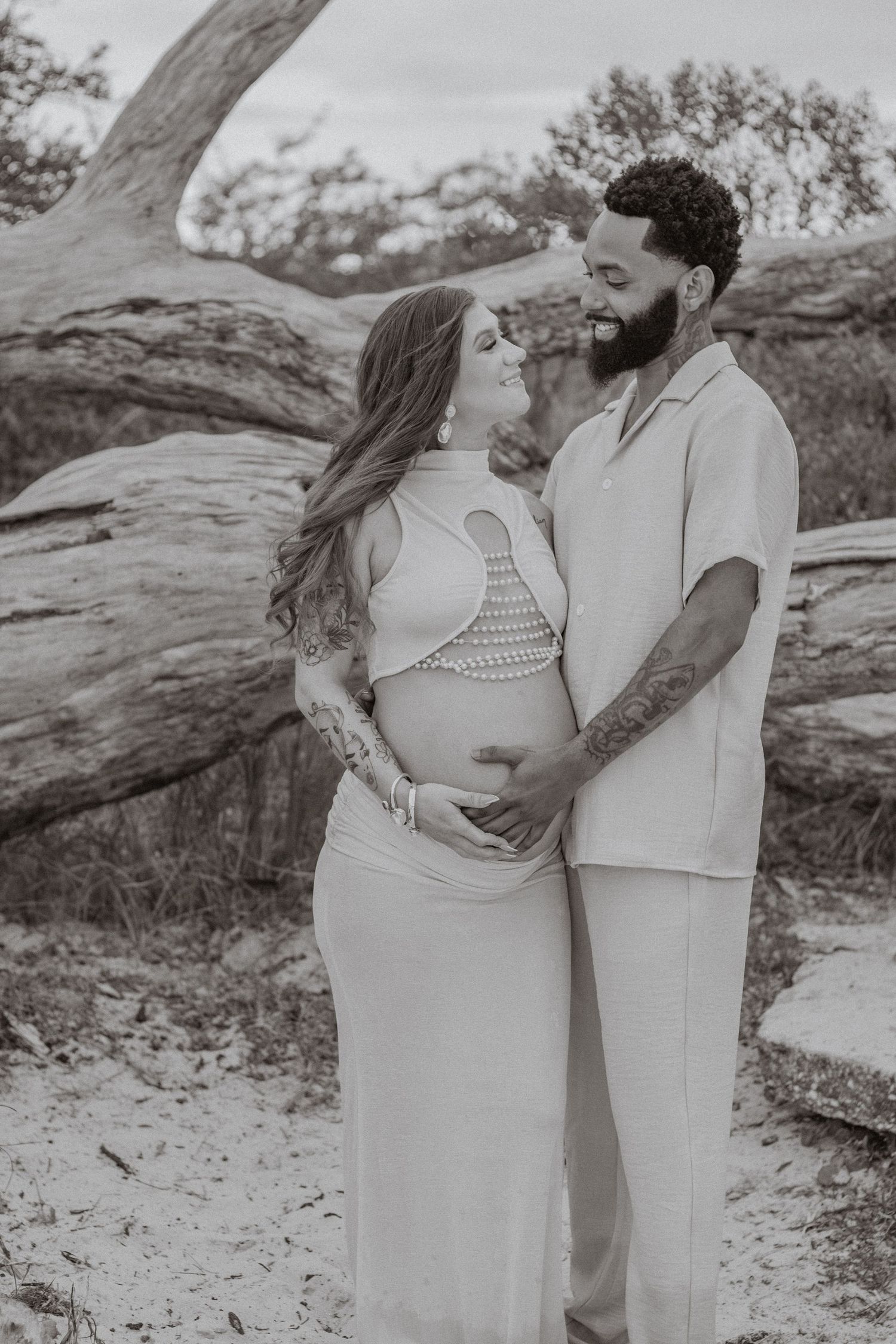 Couple embracing on Pensacola Beach during a sunset maternity photography session