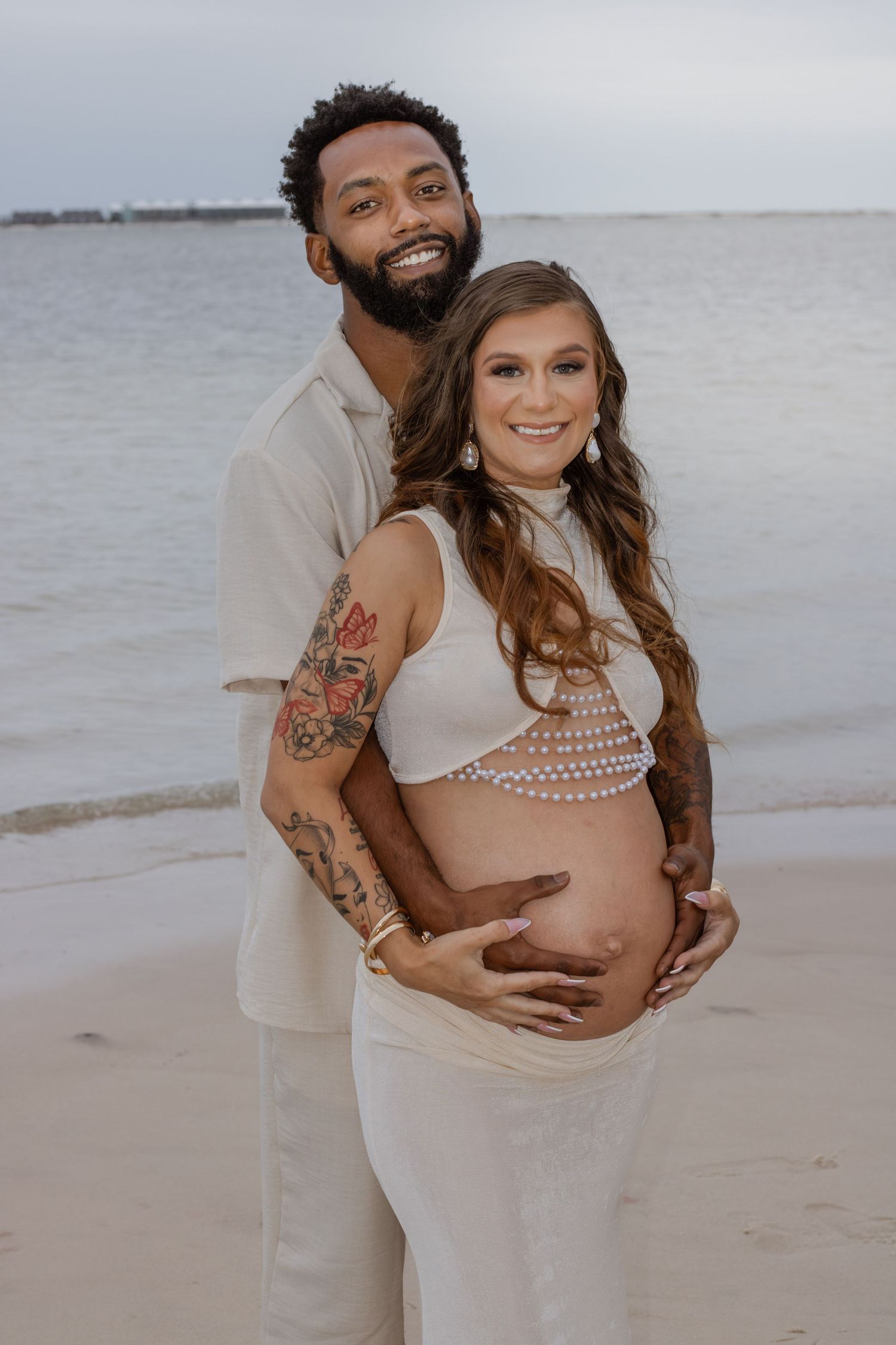 Couple embracing on Pensacola Beach during a sunset maternity photography session