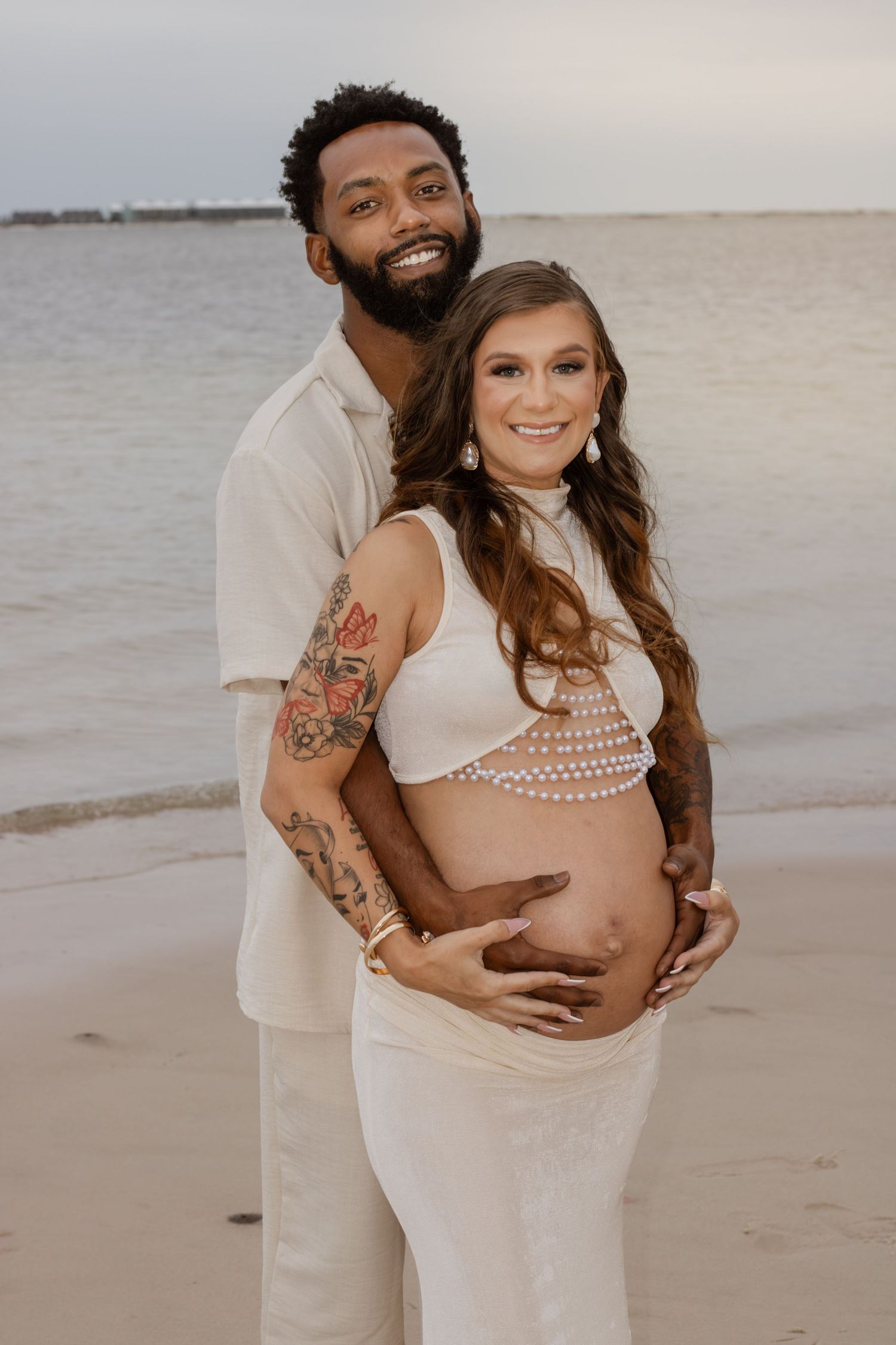 Couple embracing on Pensacola Beach during a sunset maternity photography session