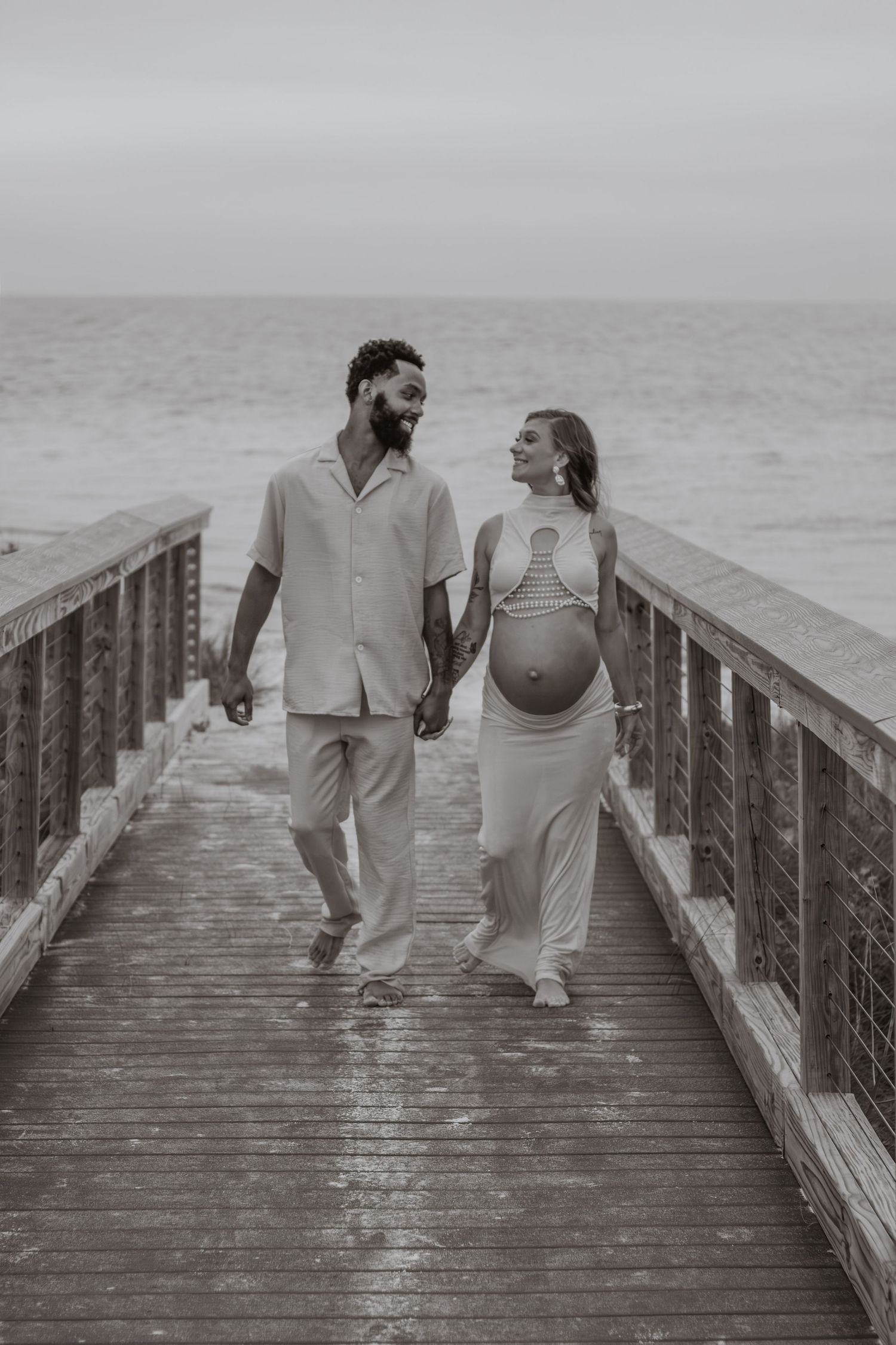 Couple embracing on Pensacola Beach during a sunset maternity photography session