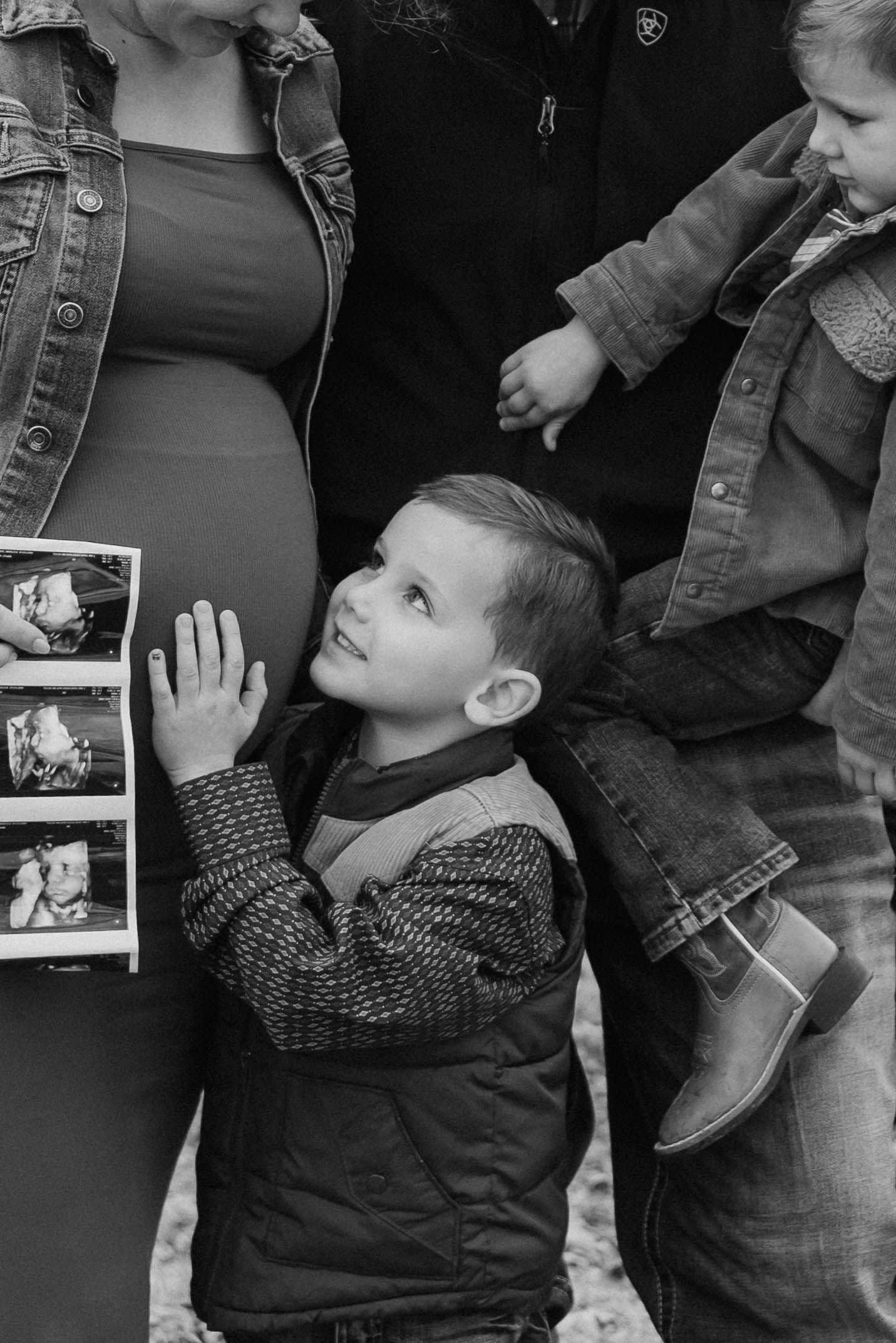 Young child reaches up excitedly while looking at polaroid photos in black and white composition.