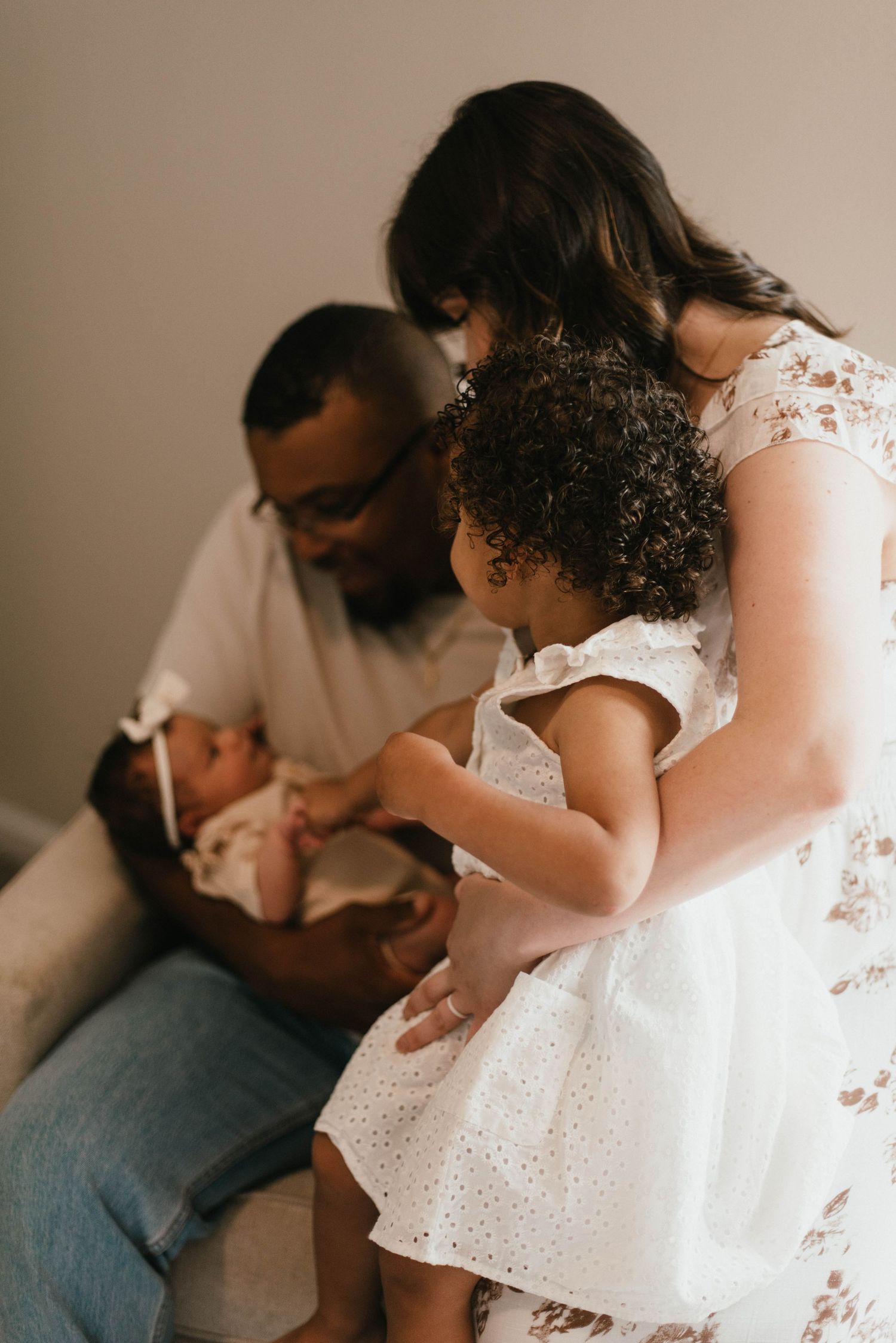 Intimate family portraits captured in soft indoor lighting with white attire.