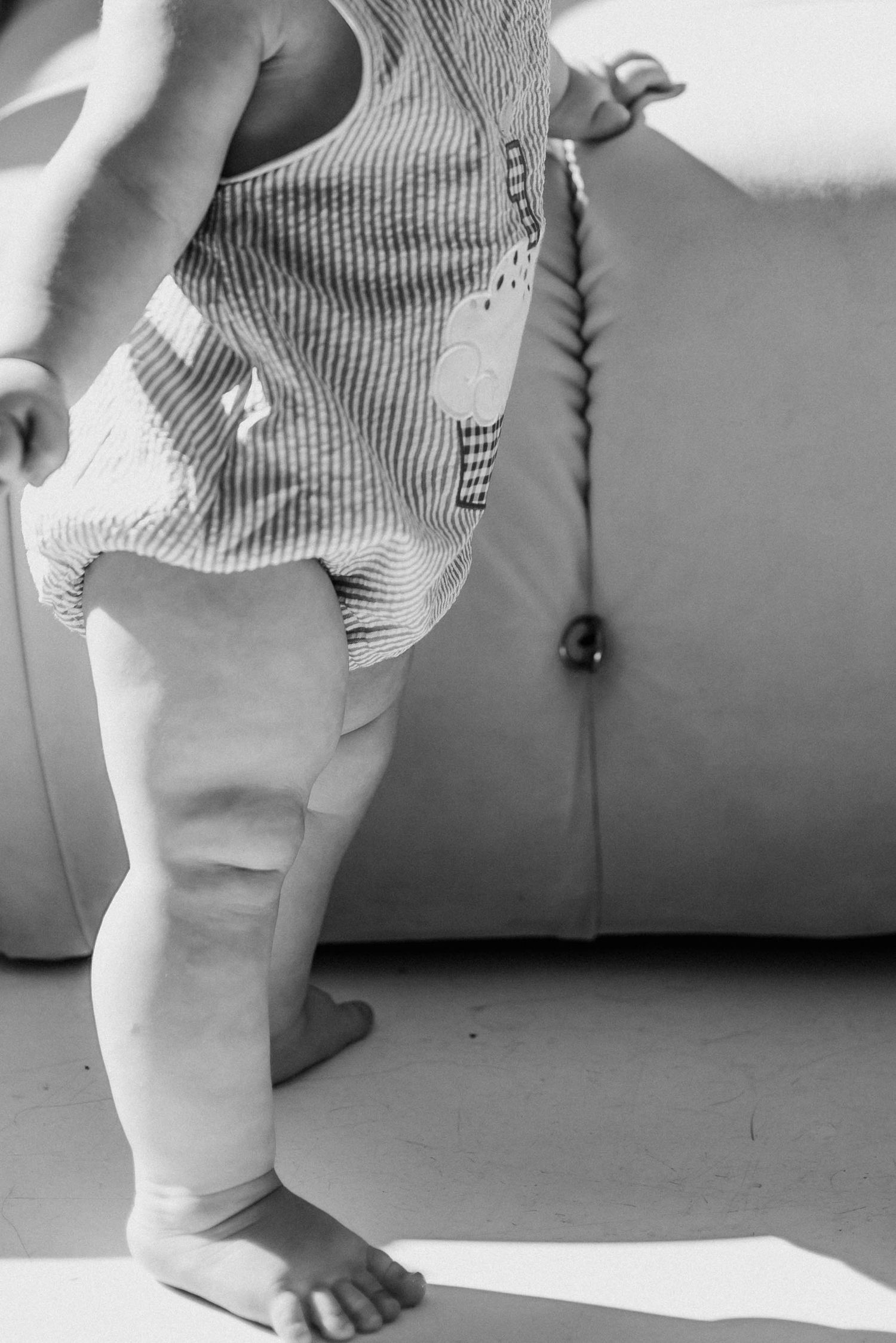 Close-up of baby feet and striped clothing against light background.