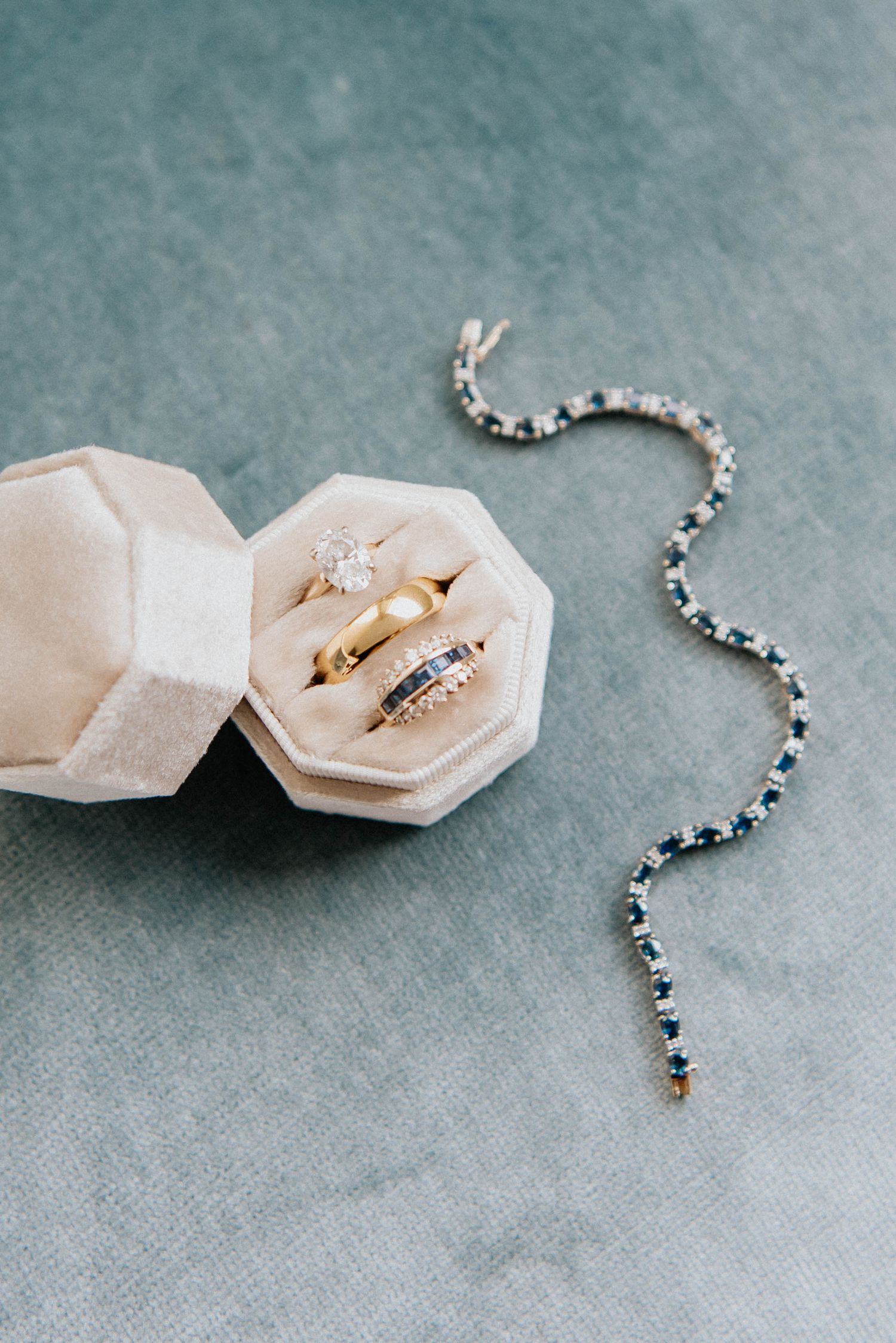 Wedding rings and jewelry displayed on light grey background with delicate styling.