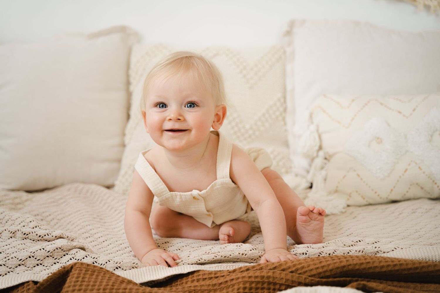 lachende baby tijdens een sittersessie in studio in tijdloze setting in Zandhoven