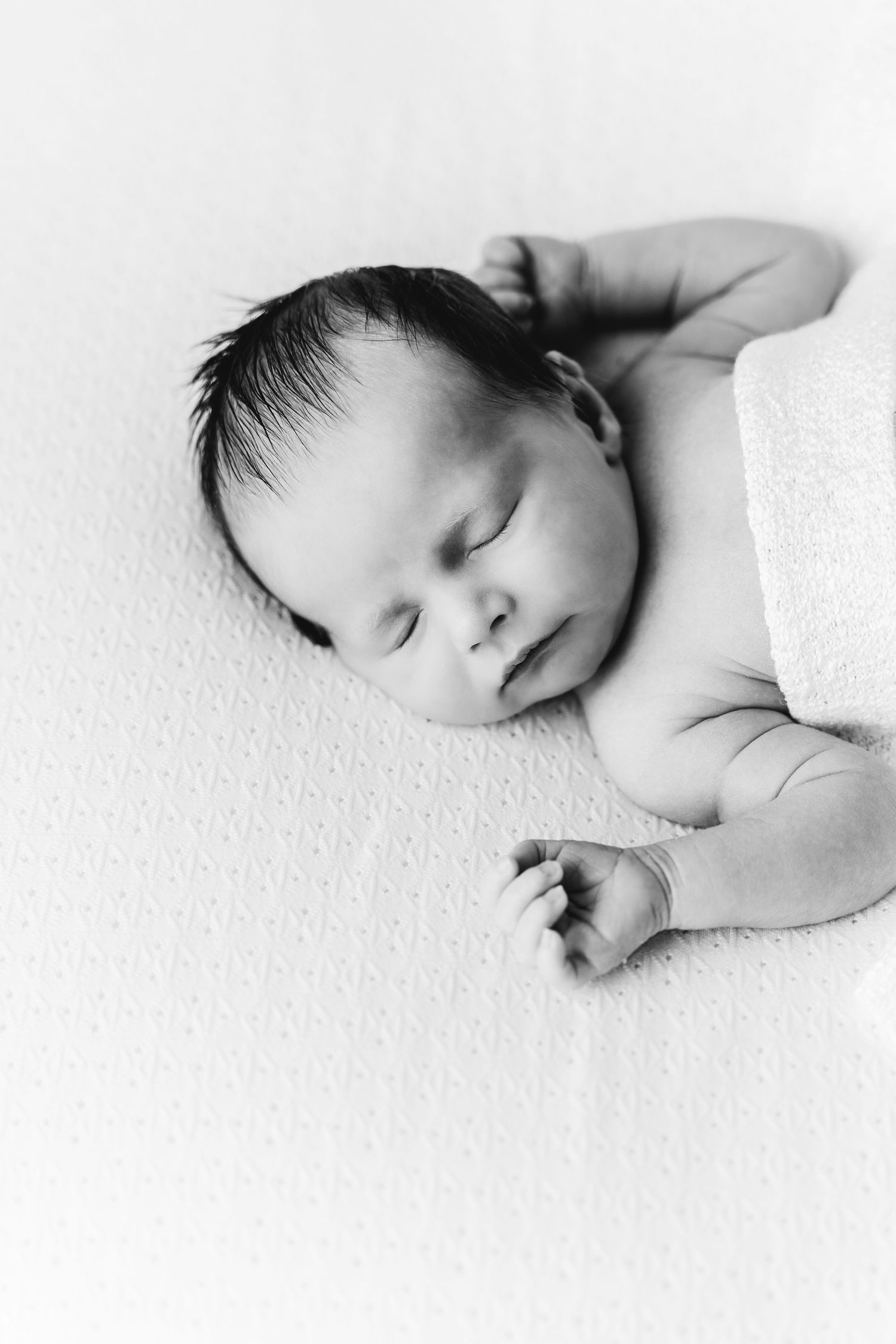 een zwartwit foto van een slapende baby in een tijdloze setting tijdens een newborn reportage in studio in zandhoven