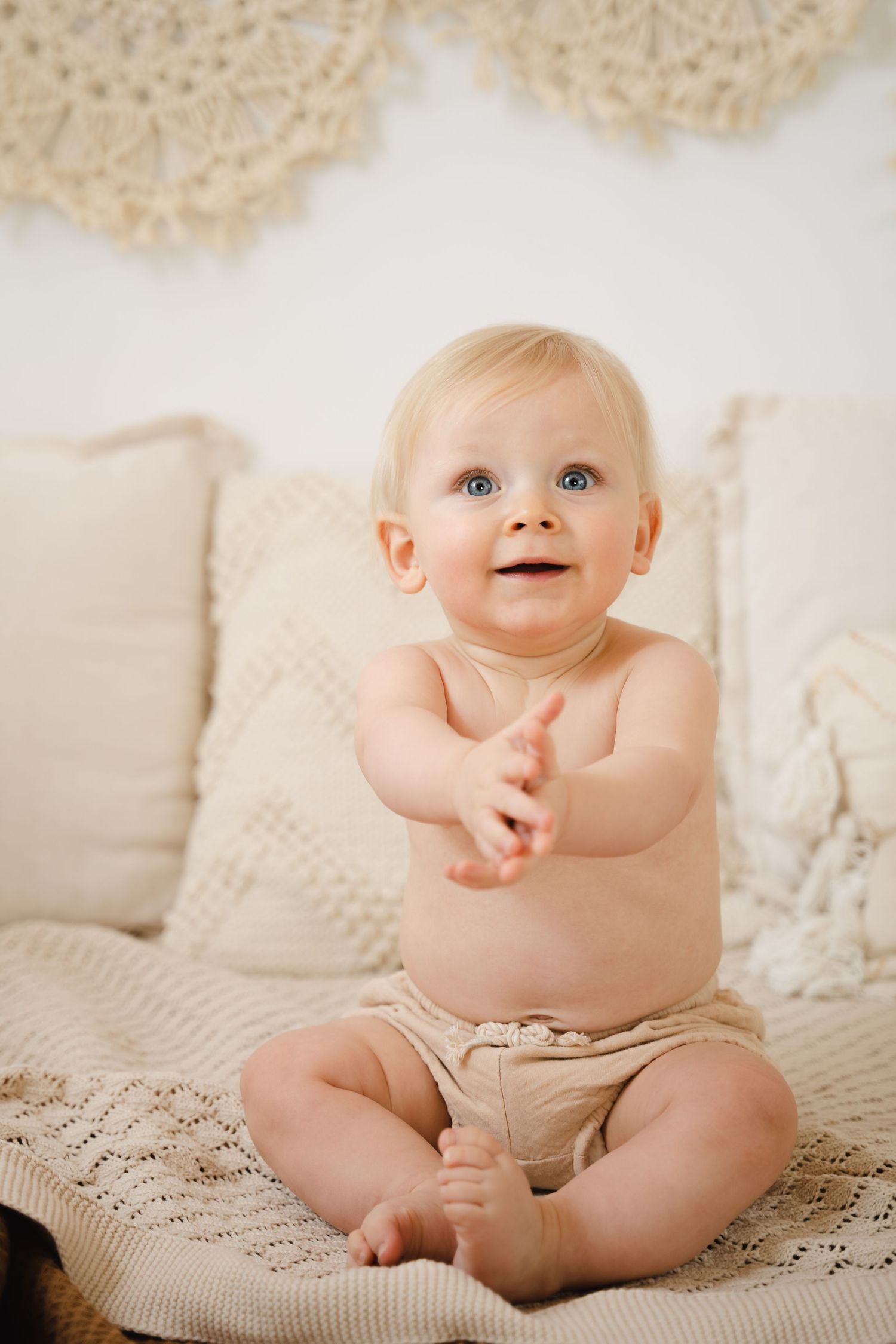foto van vrolijke baby die net kan zitten tijdens sittersessie in fotostudio in zandhoven
