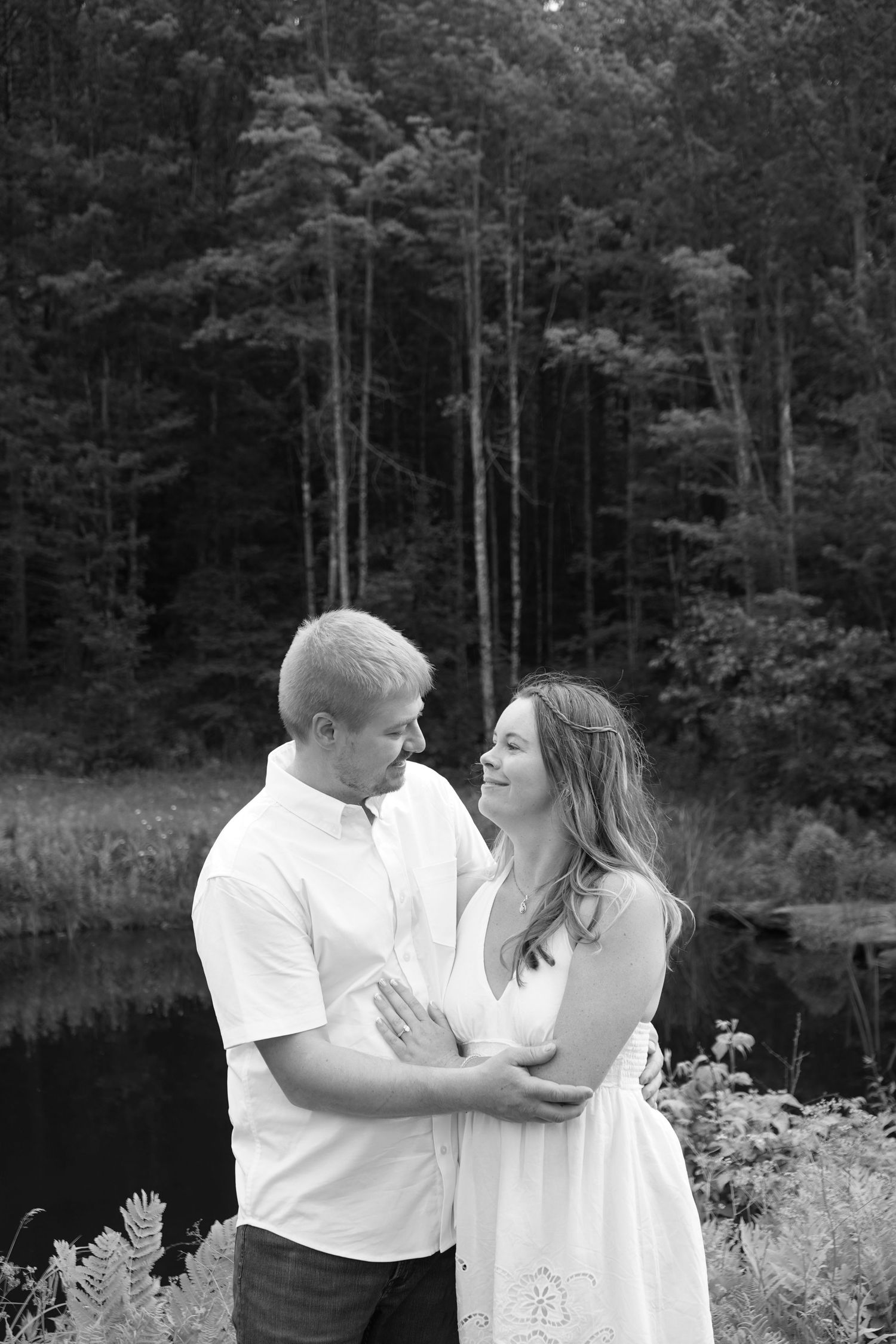 black and white image of couple in front of pond