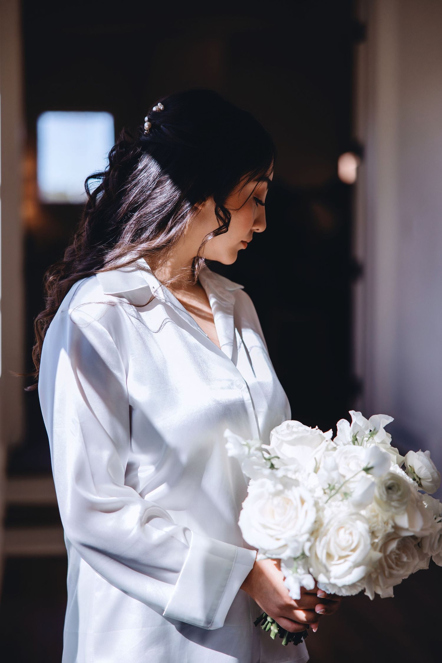 Bride in a robe holding her bouquet while getting ready