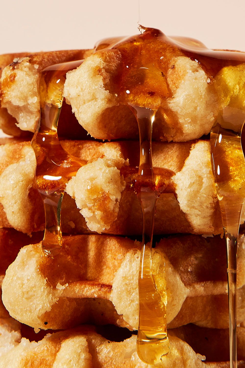 Stack of fluffy waffles drizzled with golden honey flowing down the sides.
