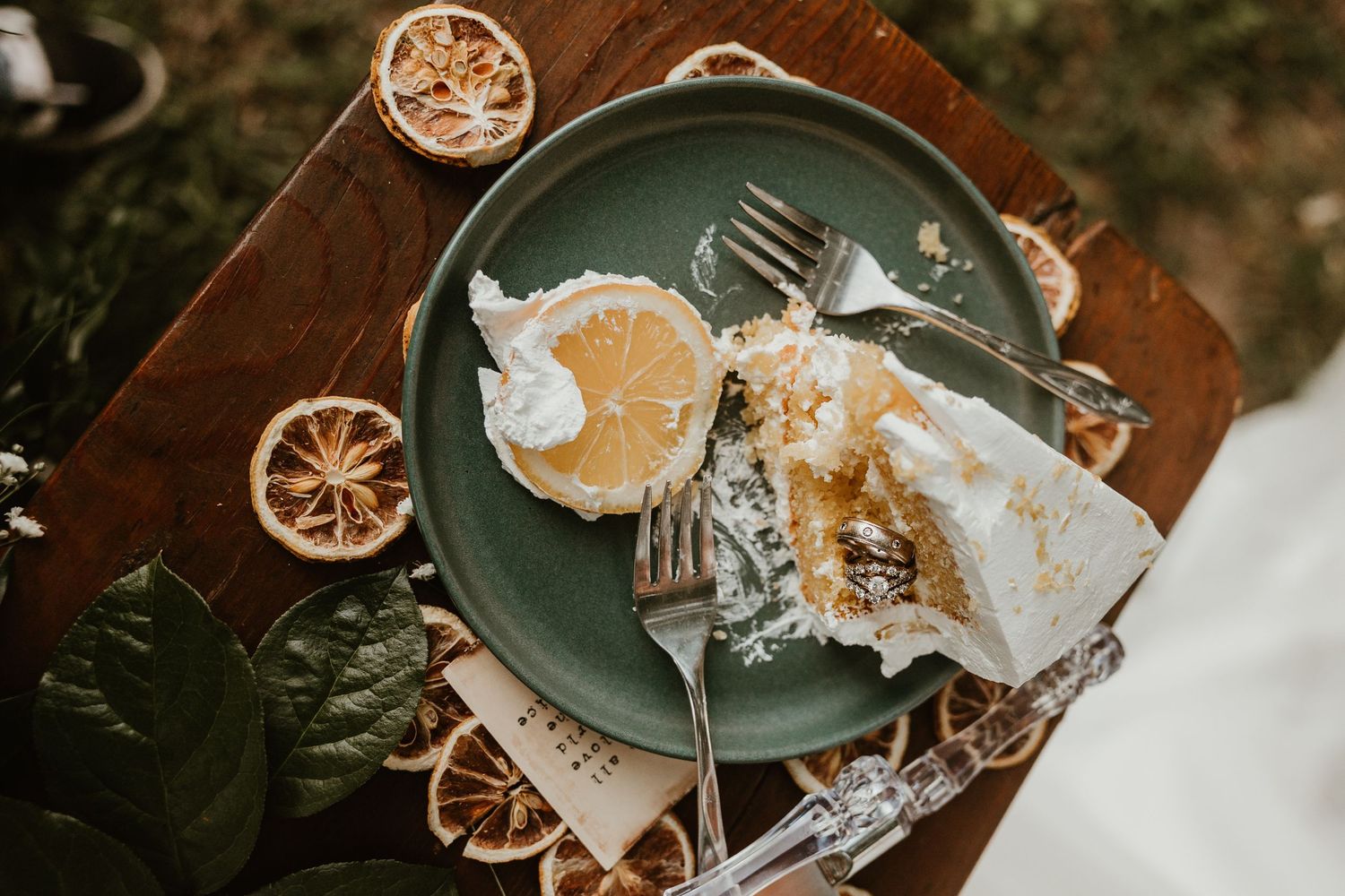 Dried citrus slices and scattered white paper pieces arranged artistically on dark plates in a rustic setting.