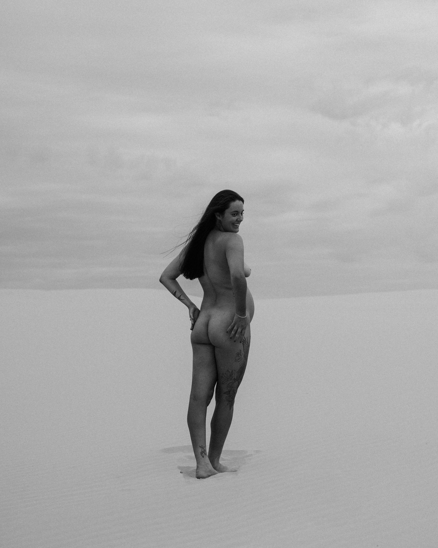 Black and white silhouette of someone walking along a sandy beach.