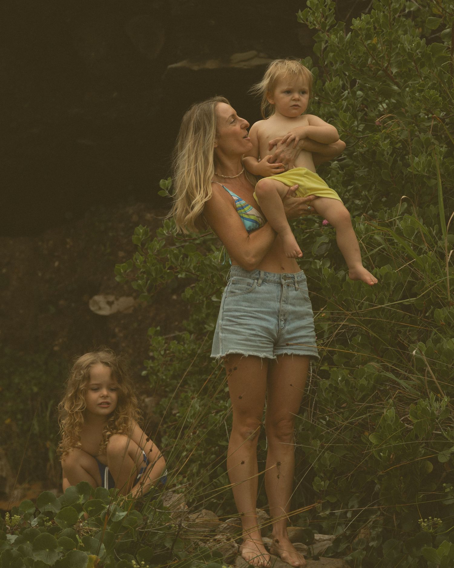 A sequence of candid outdoor photos showing playful interactions between two people in casual summer attire against greenery.