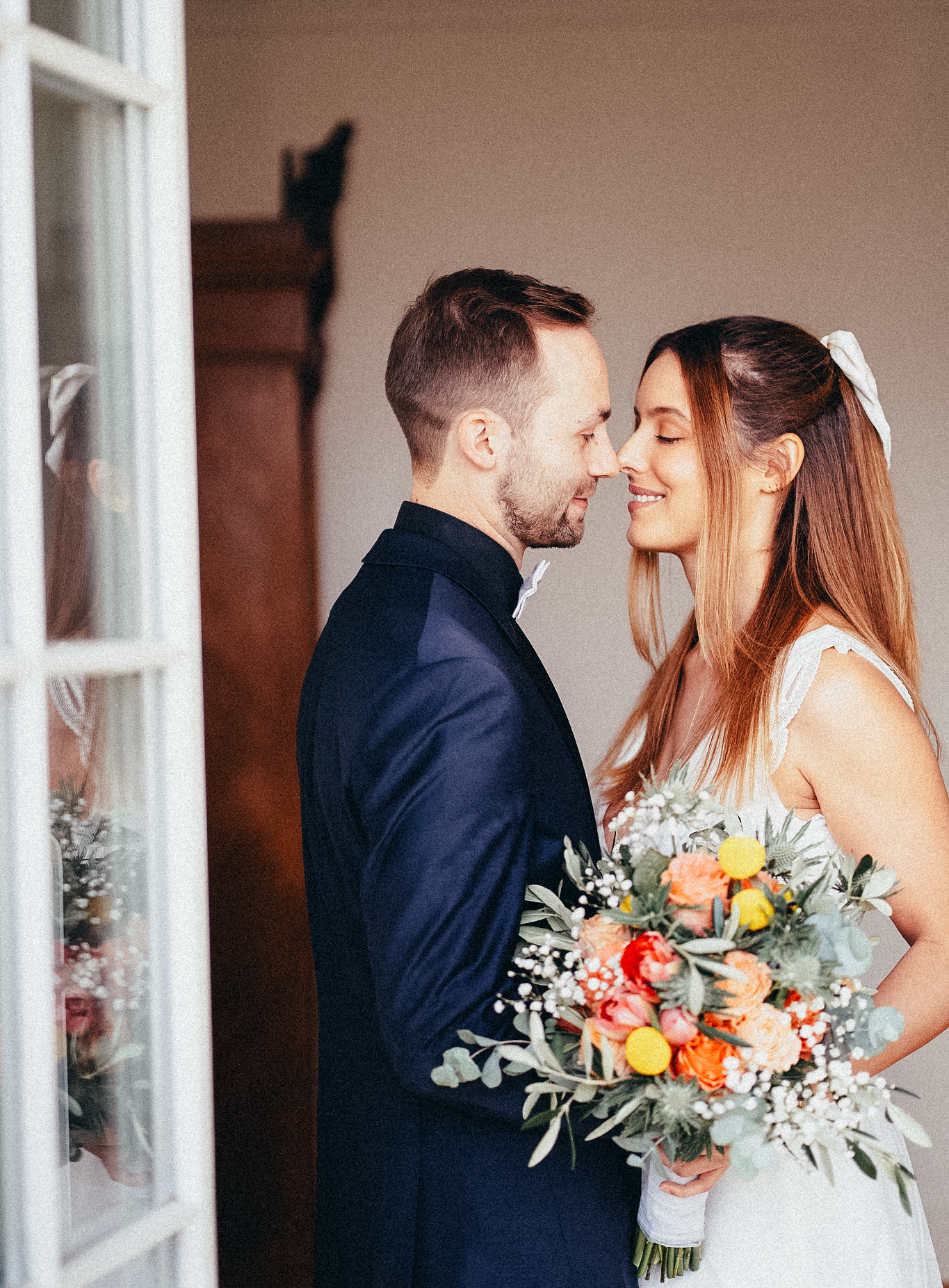 Bride and groom in intimate moment holding colorful wedding bouquet with white, orange, and yellow flowers.
