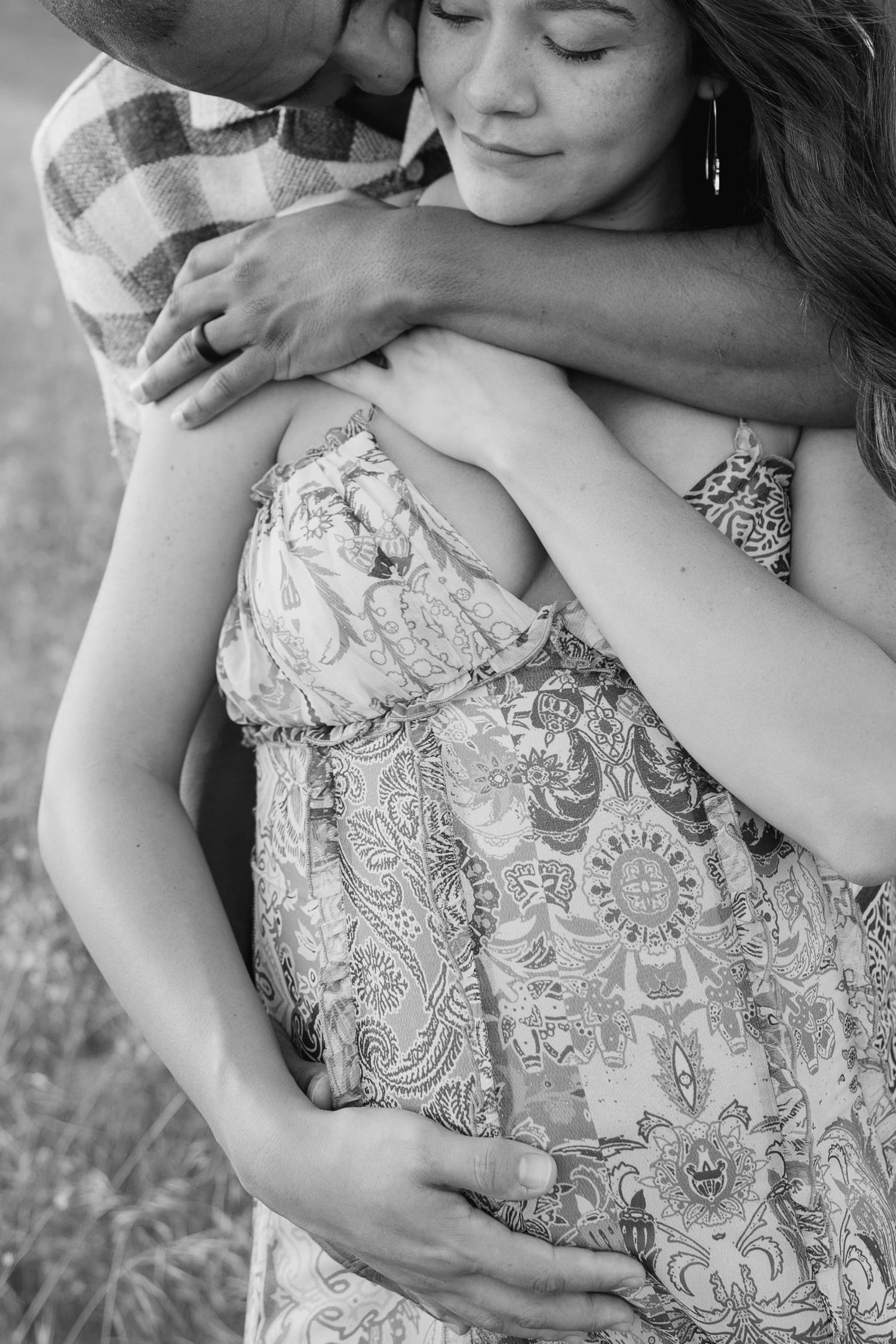 Close-up shots of couple embracing in a field, focusing on intricate lace dress details.
