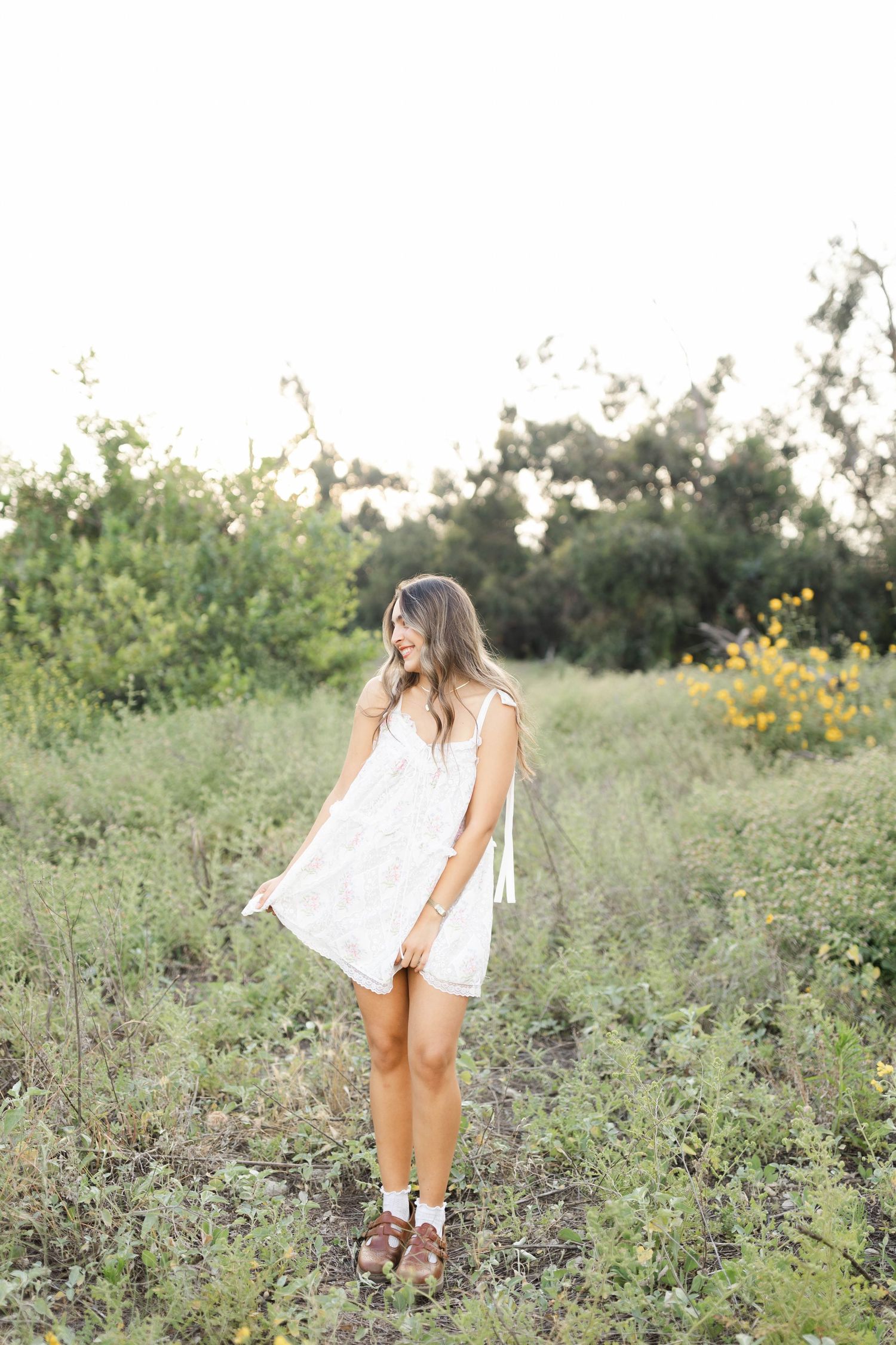 Person in white dress exploring wildflower field during golden hour photoshoot.