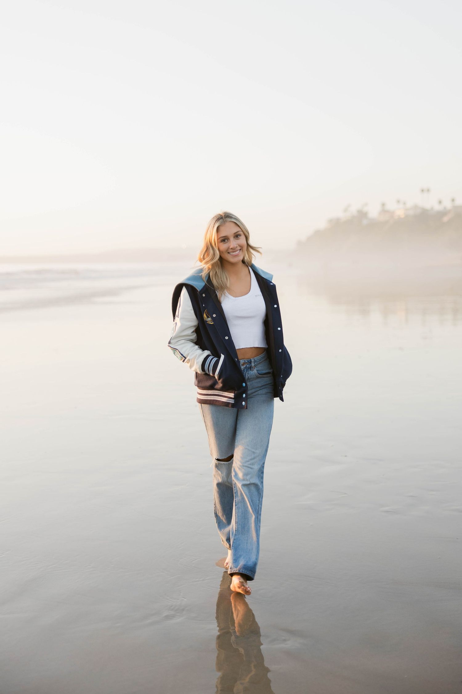 Casual beach photoshoot with denim and books on misty shoreline.