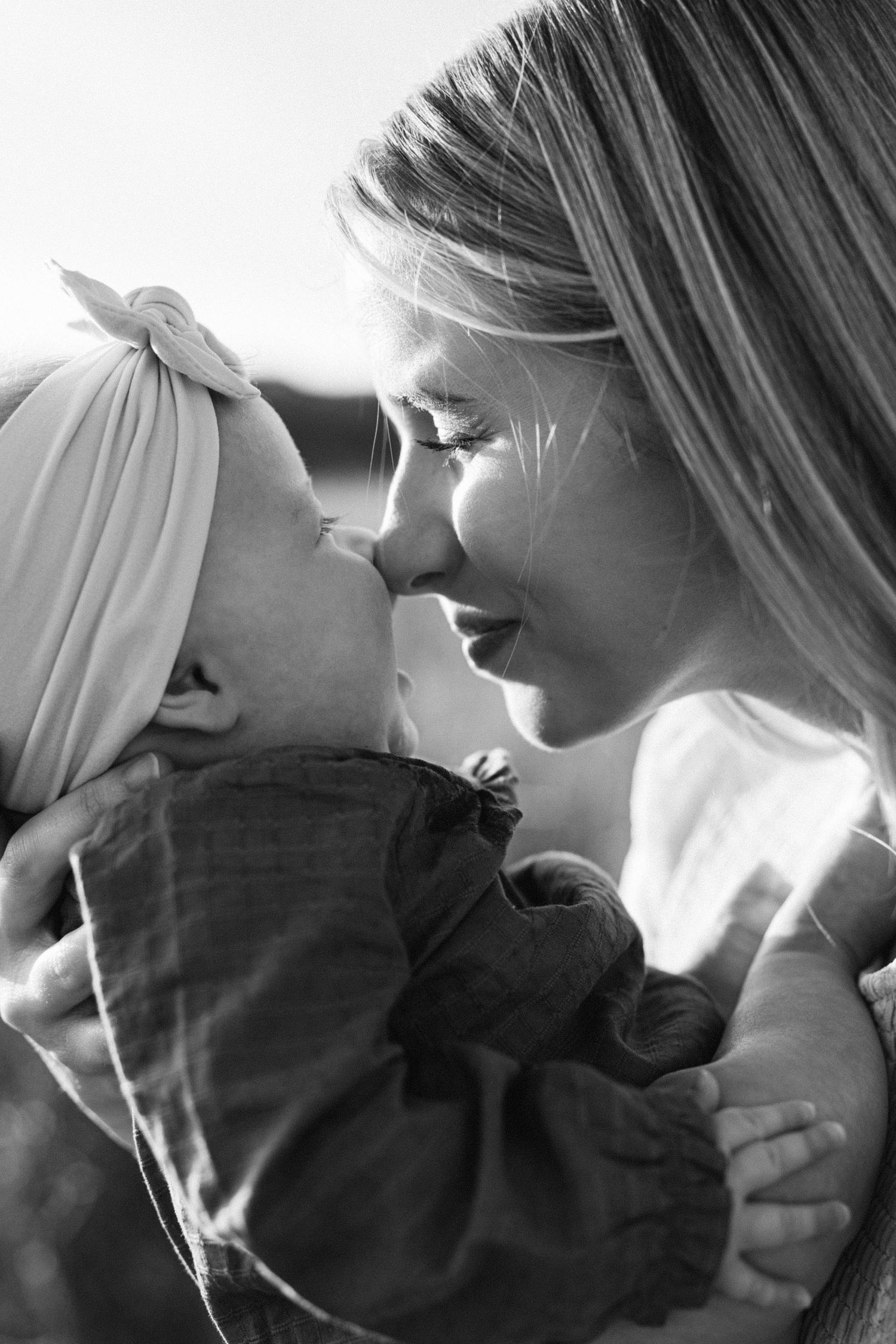 Tender black and white portrait of mother and baby sharing a close moment.