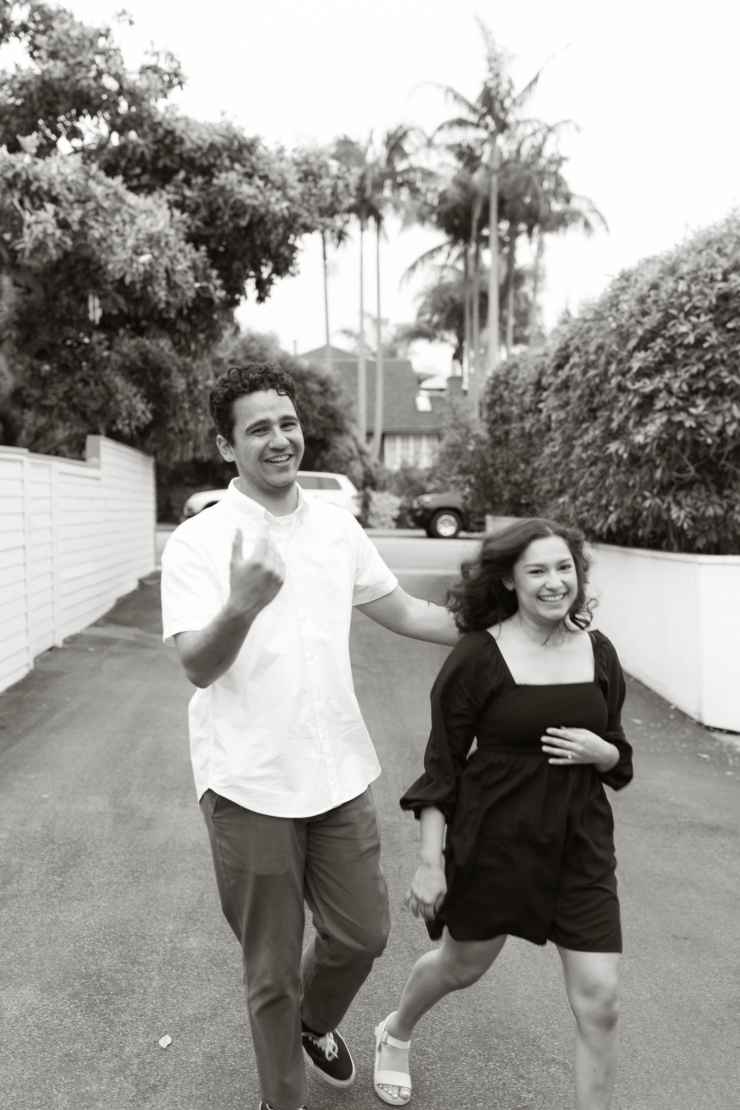 A couple runs and plays together on a palm tree lined street.