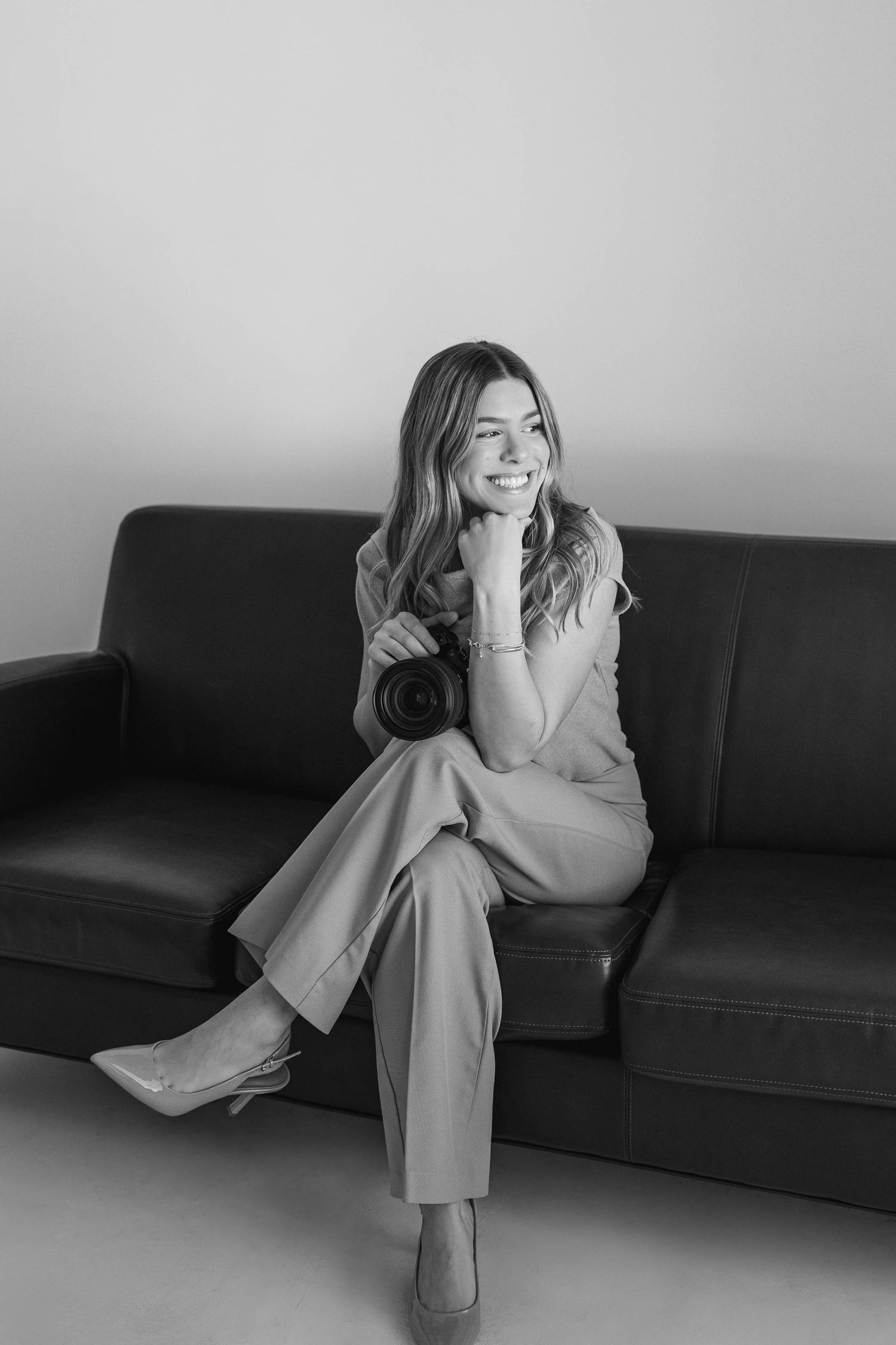 Black and white portrait series showing relaxed poses on leather sofa.