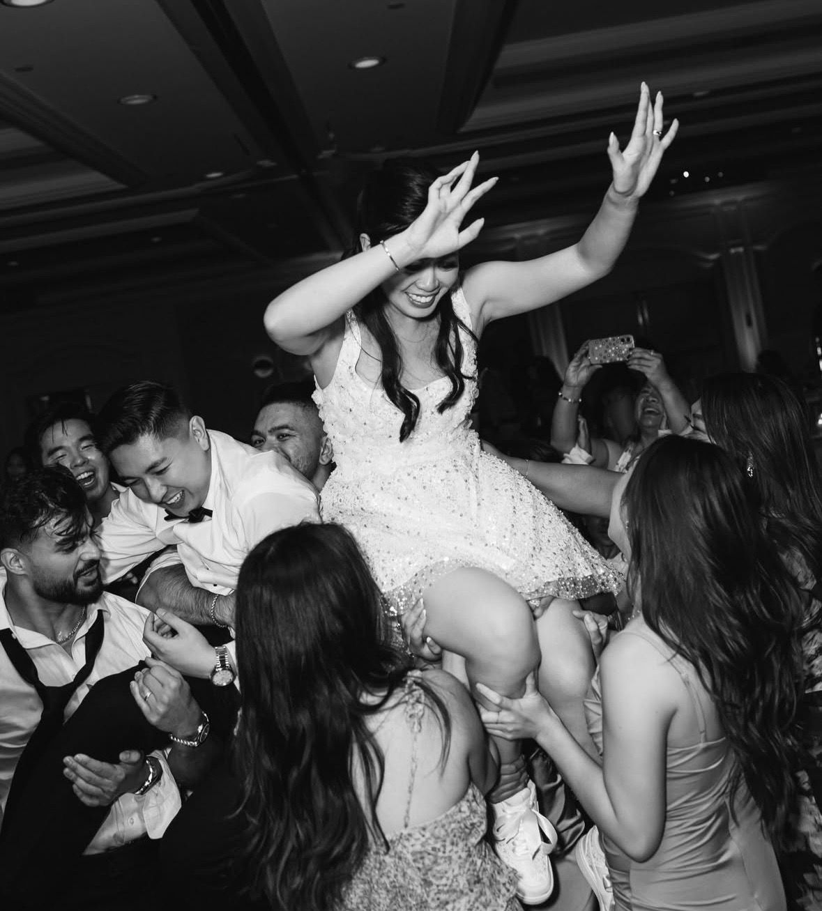 Wedding reception dance party with guests celebrating in dark lighting.
