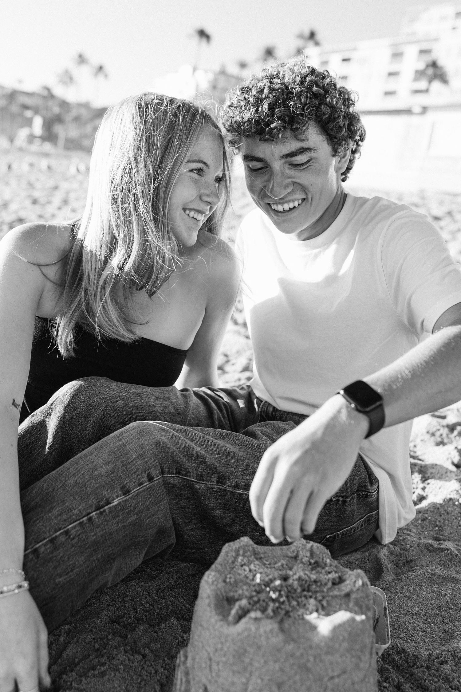 A couple lying on rocks shares a playful moment together in black and white.