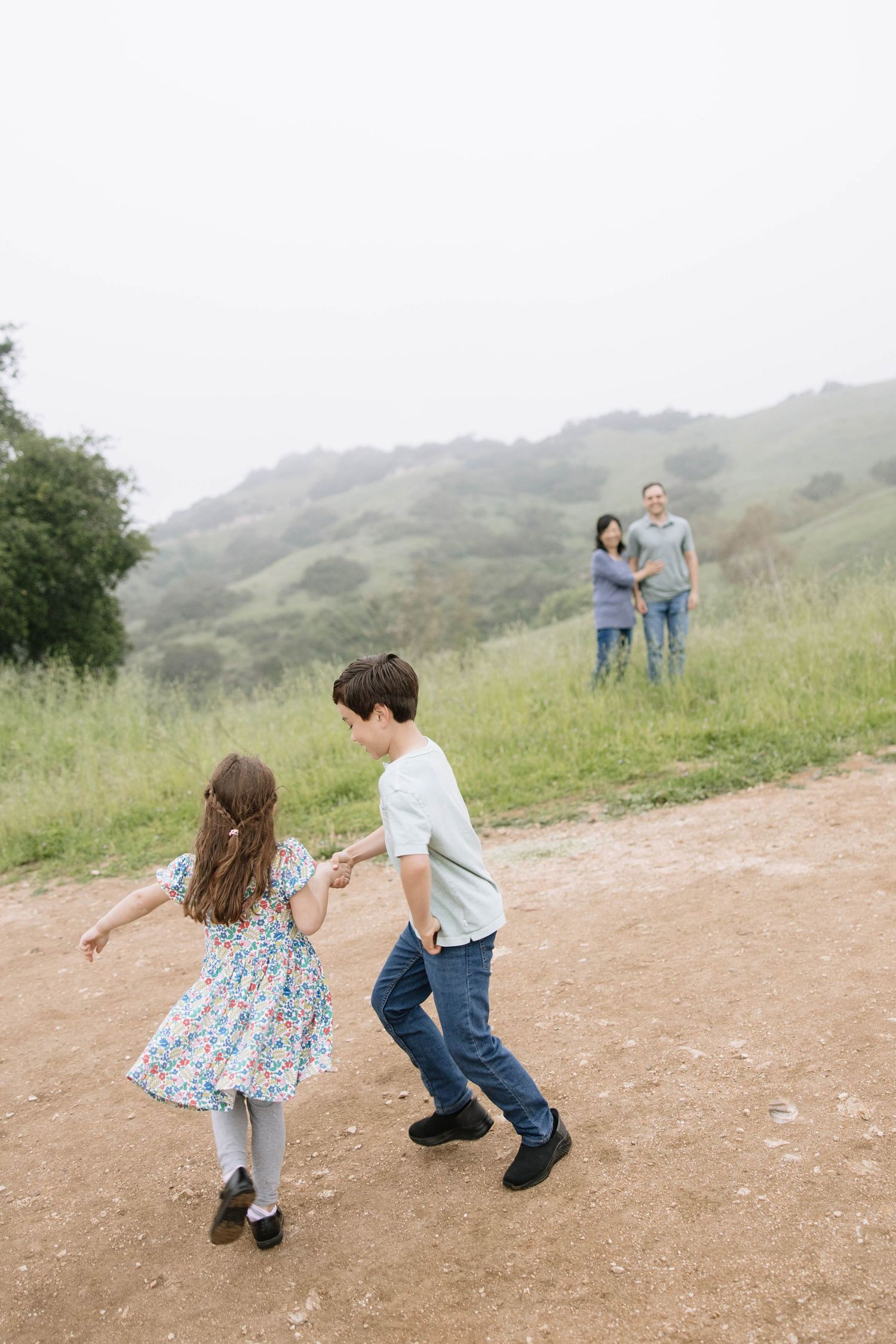 A couple dances and twirls together on a dirt path in the hills.