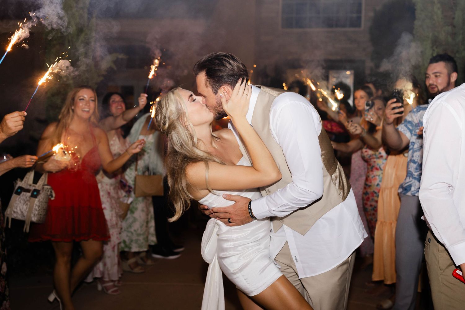 Happy couples dancing together at a lively wedding reception celebration with sparklers.