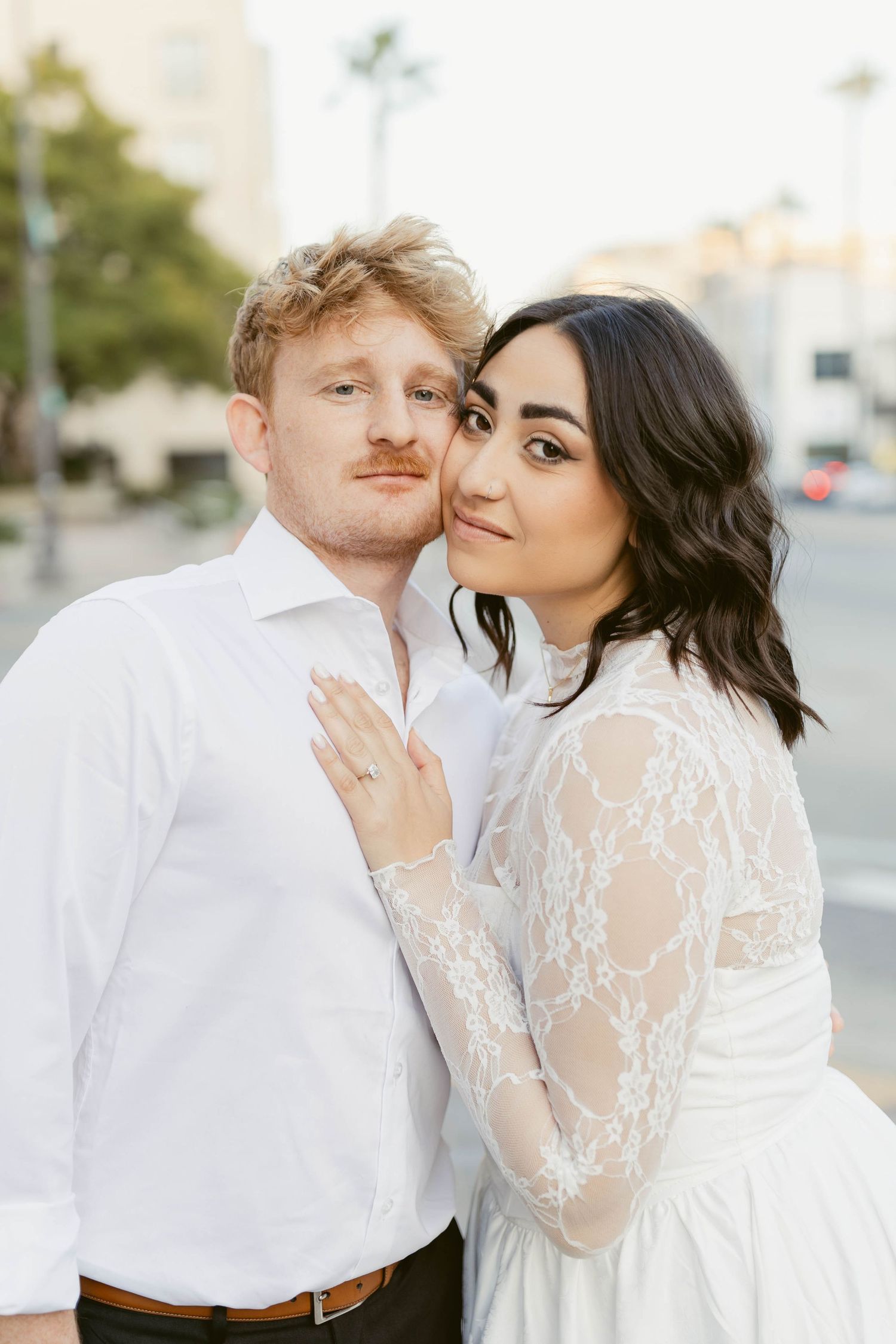A romantic couple shares intimate moments in white wedding attire against a light background.