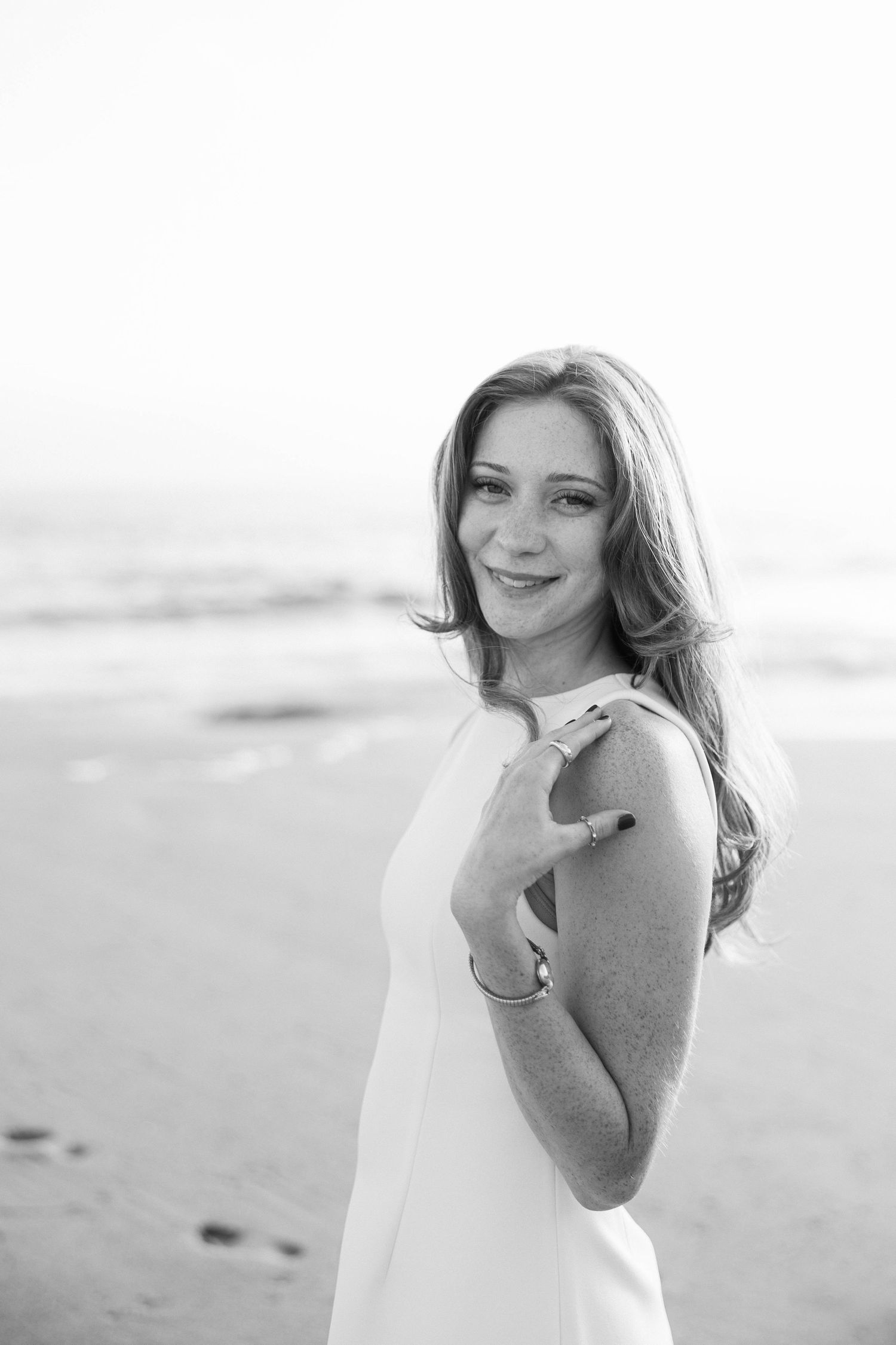 Candid beach portraits in white clothing showing natural expressions and movement.