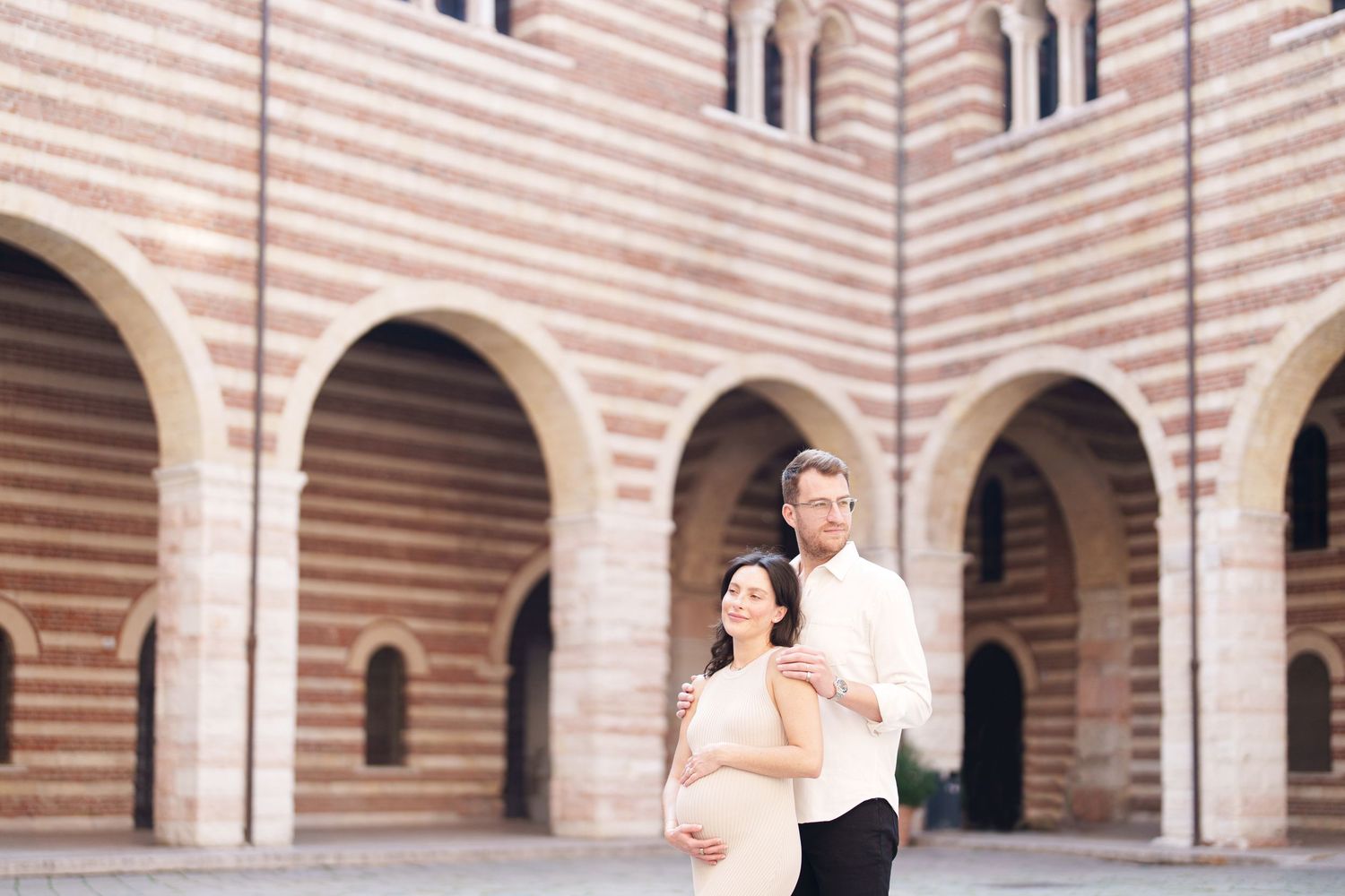 A couple dances together in an elegant stone courtyard with arched columns and striped walls.