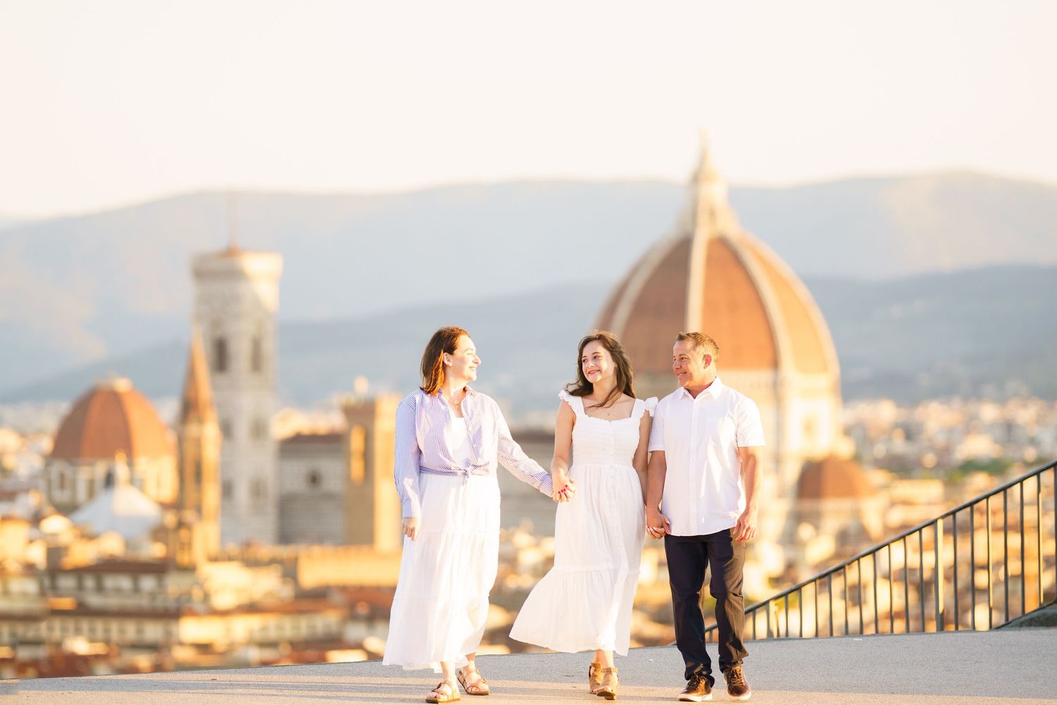 Two people in white outfits enjoy a romantic sunset view of Florence's iconic Duomo cathedral and cityscape.