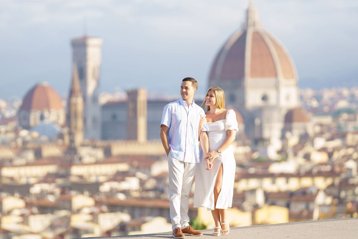 Couple enjoying romantic view of Florence cityscape with iconic Duomo cathedral dome in background.