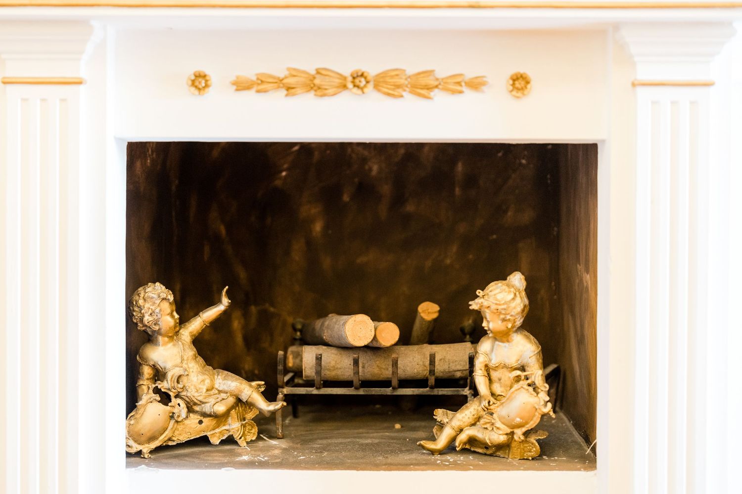 Decorative gold lions adorn an ornate fireplace mantel in an elegant room.
