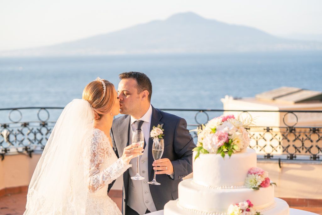A romantic wedding ceremony overlooking a scenic coastal Mediterranean landscape at sunset.
