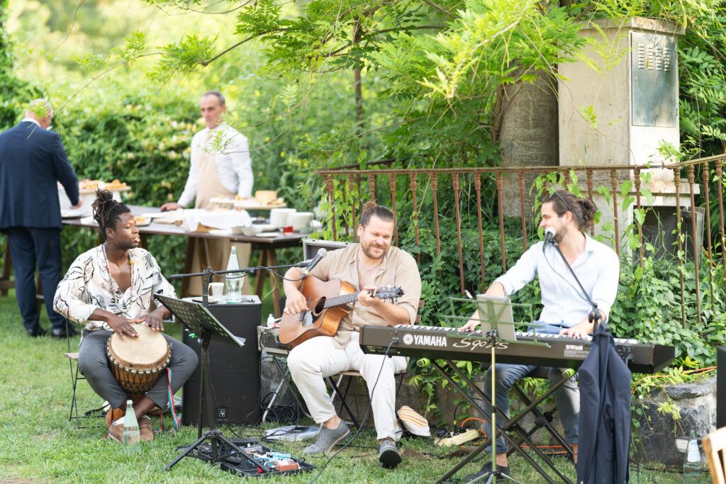 Guests relax at wooden picnic tables during outdoor garden party.