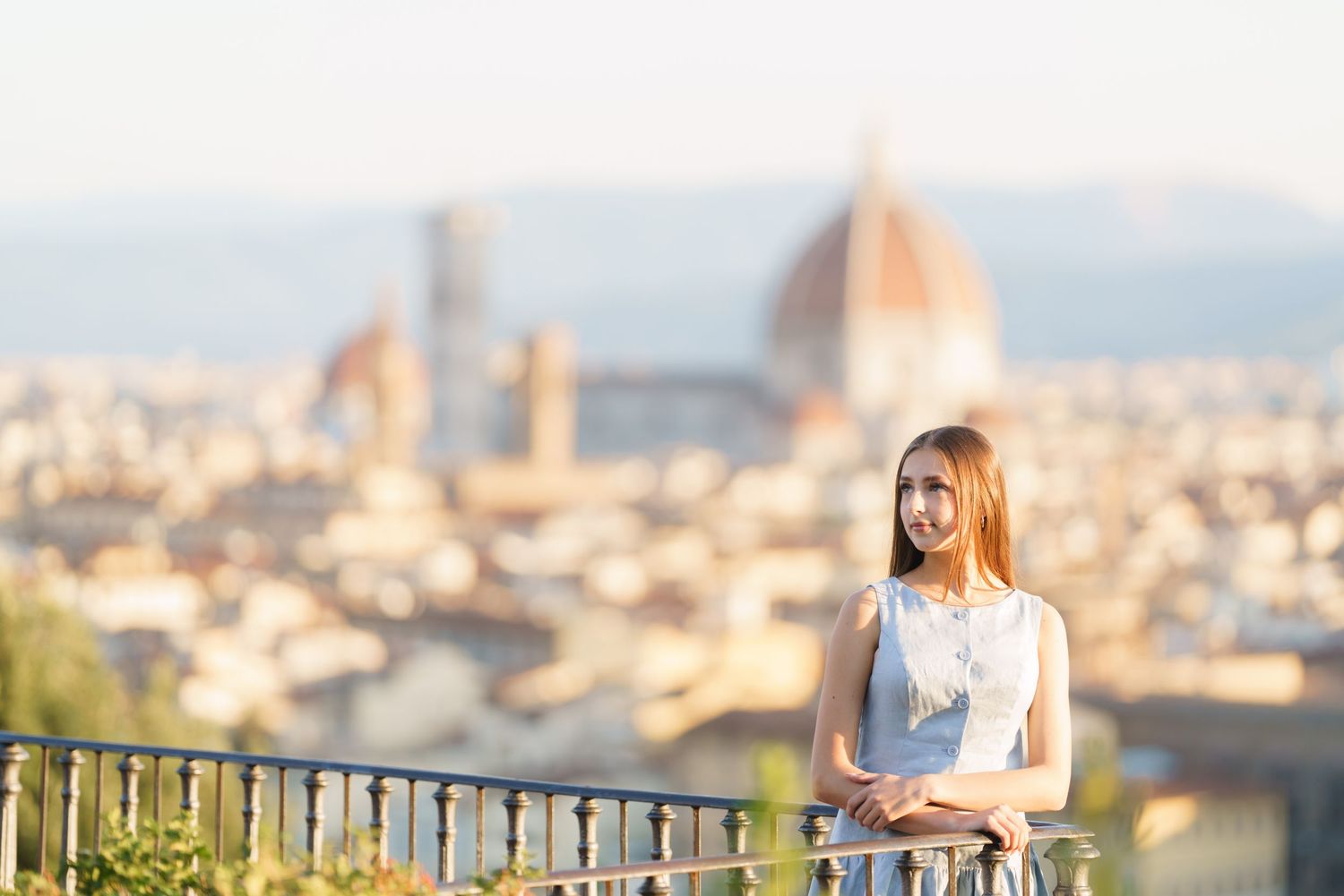 Person admiring the stunning cityscape view of Florence, Italy from Piazzale Michelangelo at sunset.