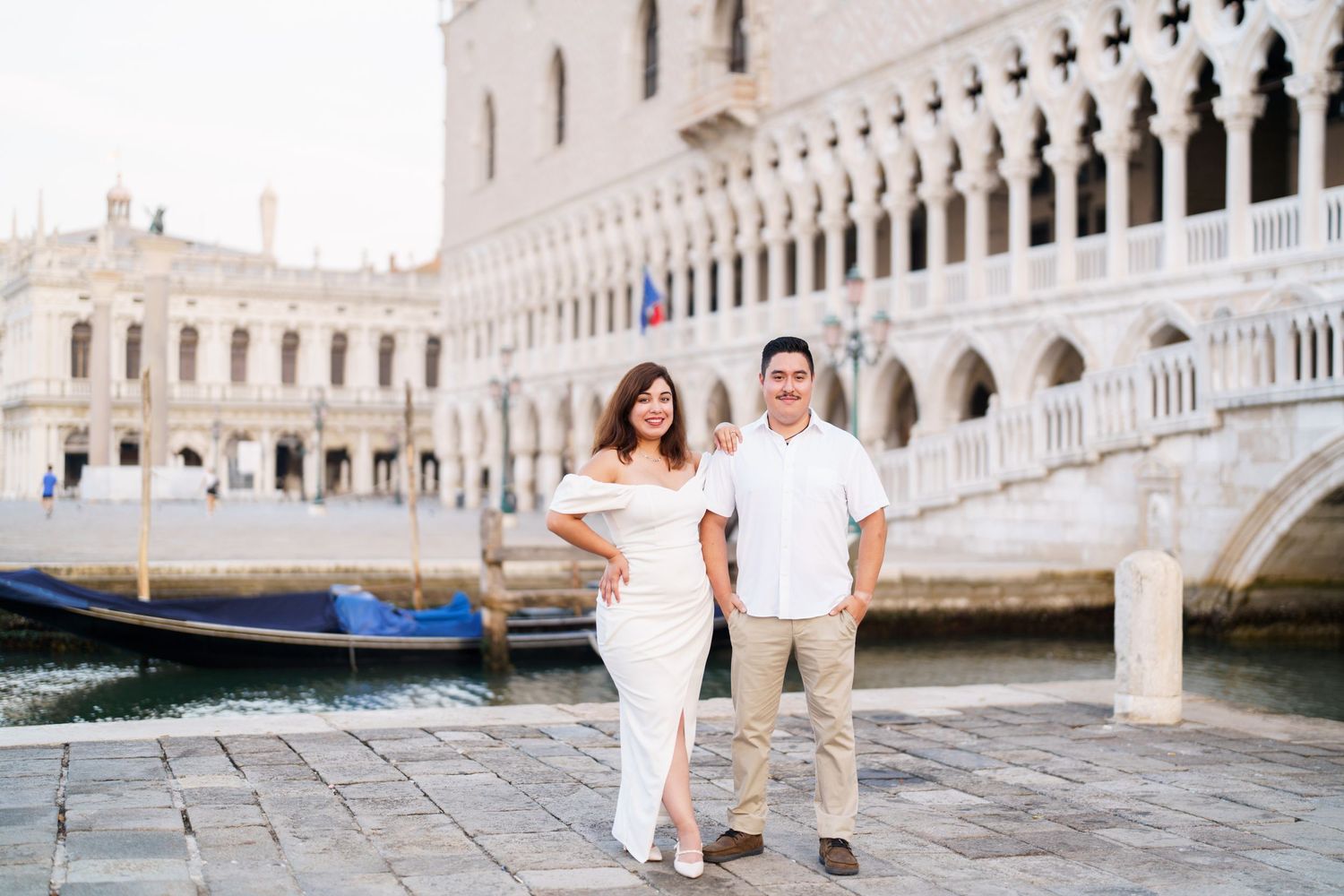 A couple in white outfits poses for romantic photos along the canals and bridges of Venice, Italy.